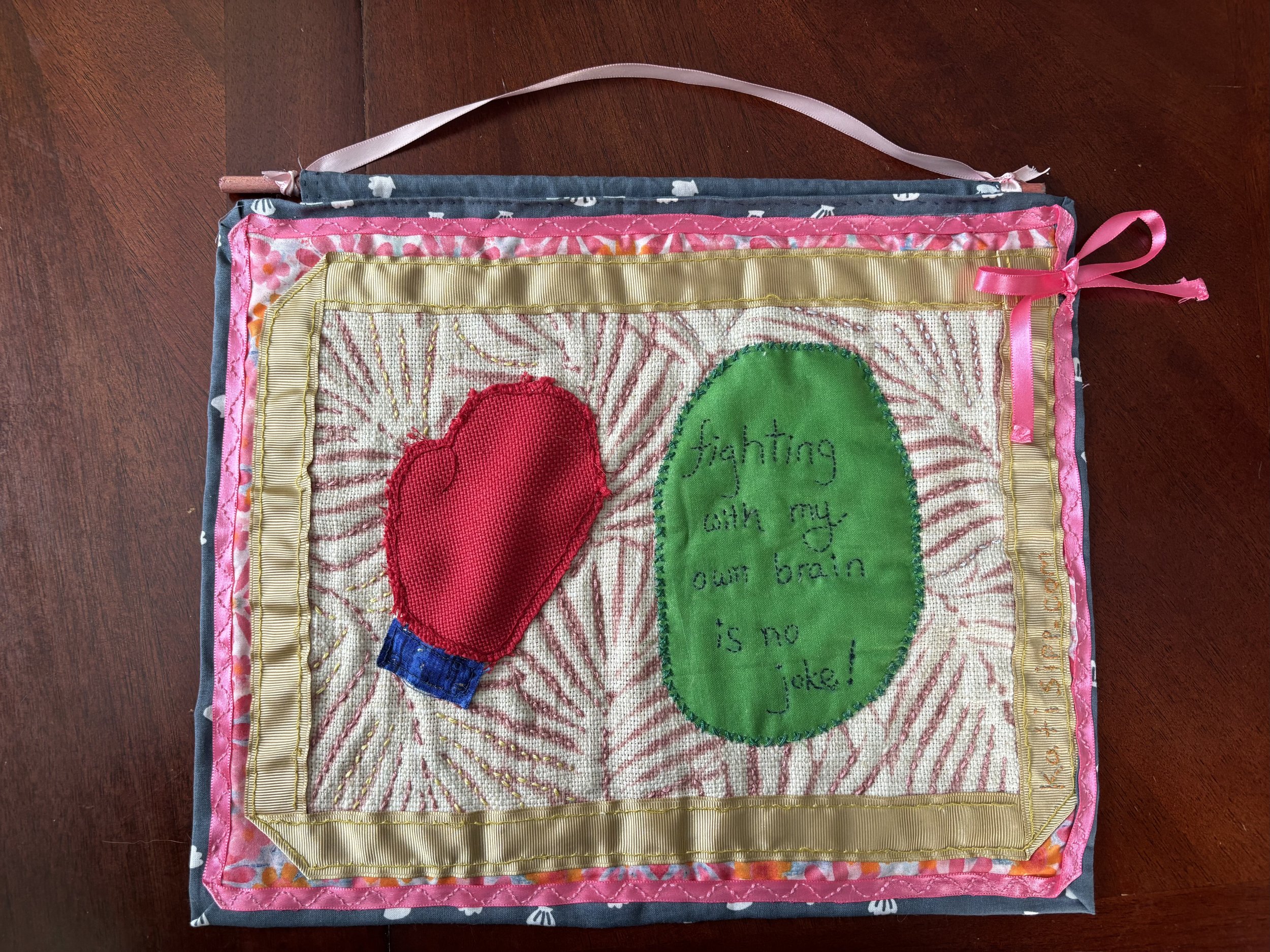 a fabric wall hanging that reads "fighting with my own brain is no joke!" and shows a boxing glove