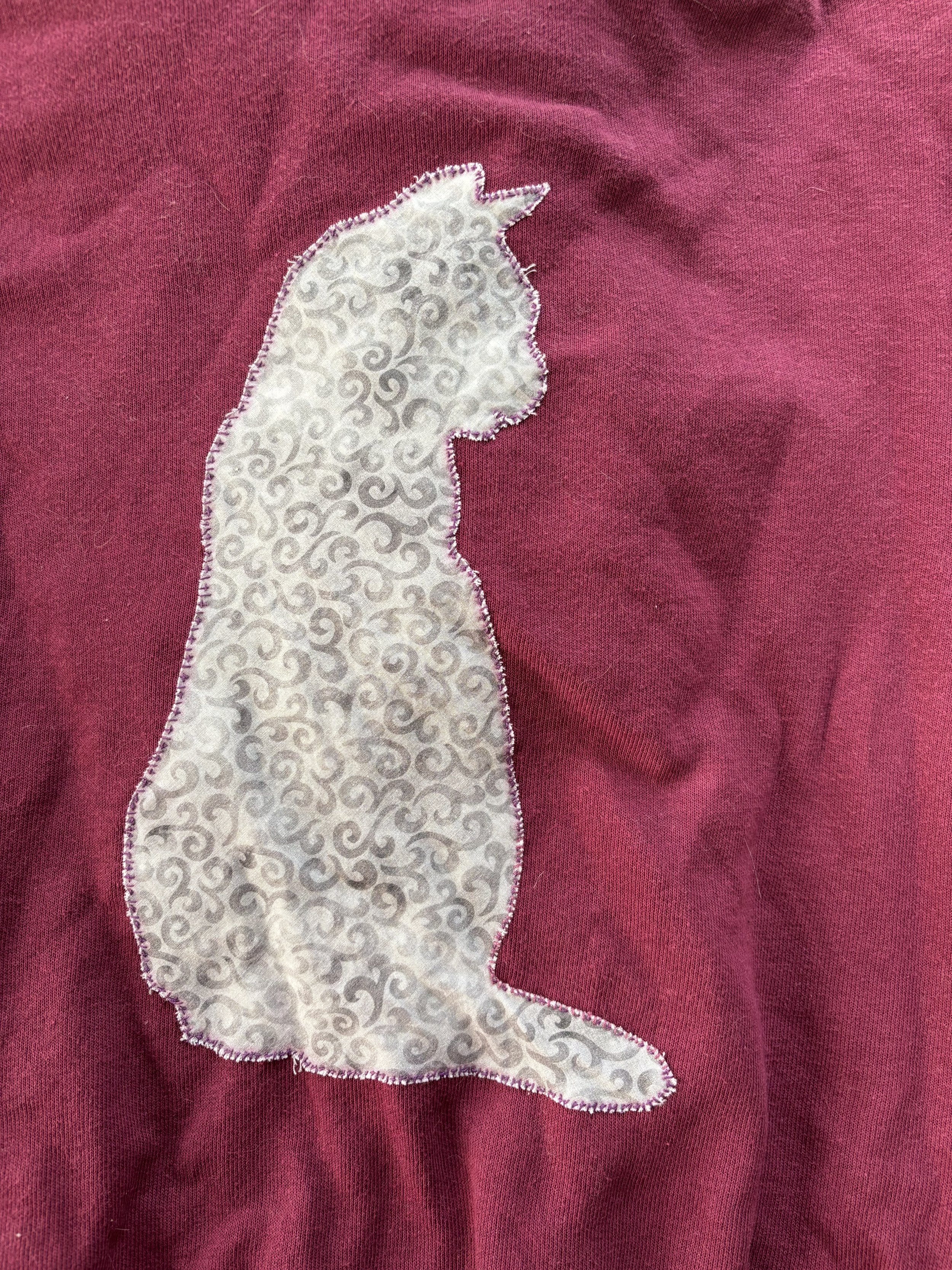 close up of appliquéd cat on back of maroon hoodie