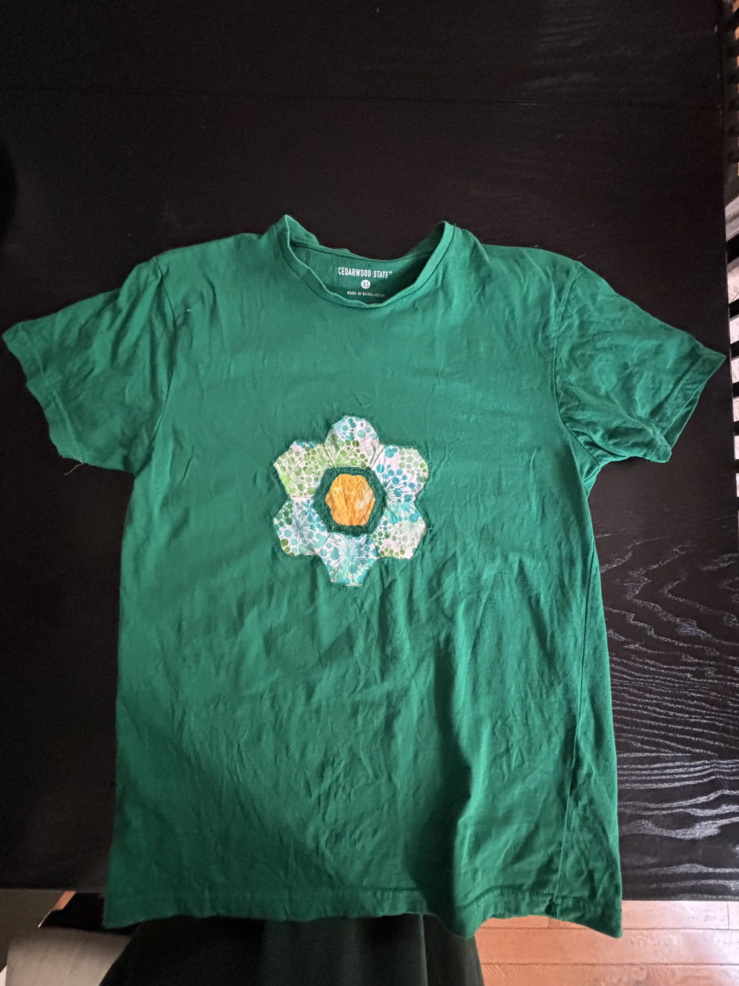 green t-shirt with reverse-appliqued hex flower