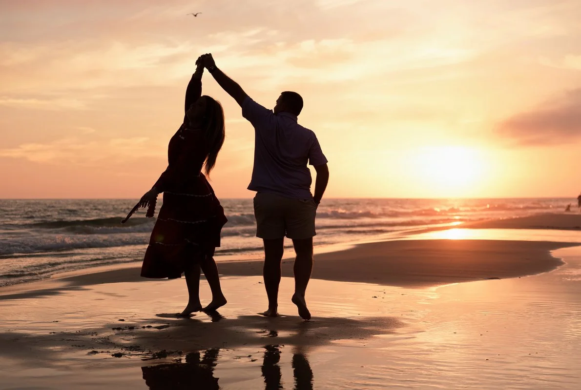 Silhouettes of a couple dancing on the Gulf Shores beach during sunset, with the ocean and sky in the background.