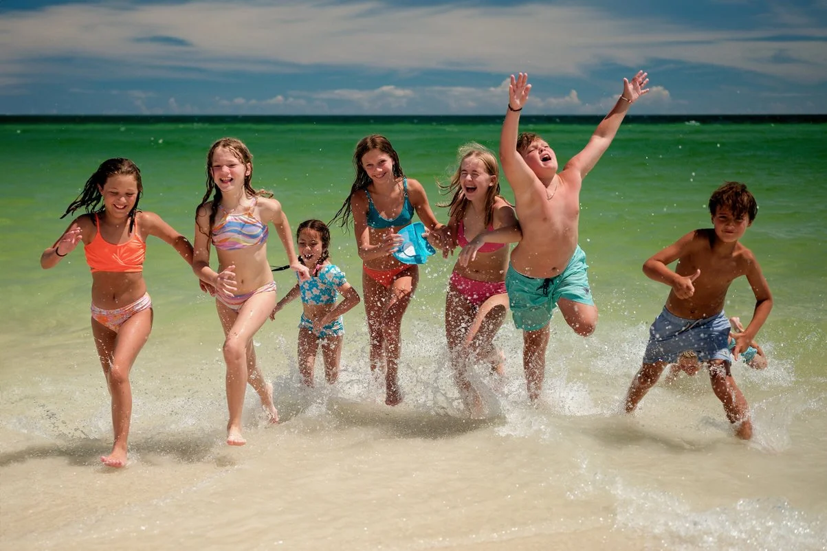 Group of children playing and running in the ocean waves at the beach on a sunny day.