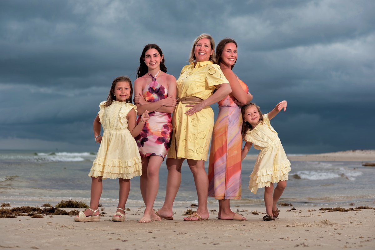 A multigenerational family of five women and girls standing on the beach in Kiva Dunes. The women are dressed in colorful summer dresses, and the young girls wear yellow dresses. Off Camera flash was used on a stormy evening. 