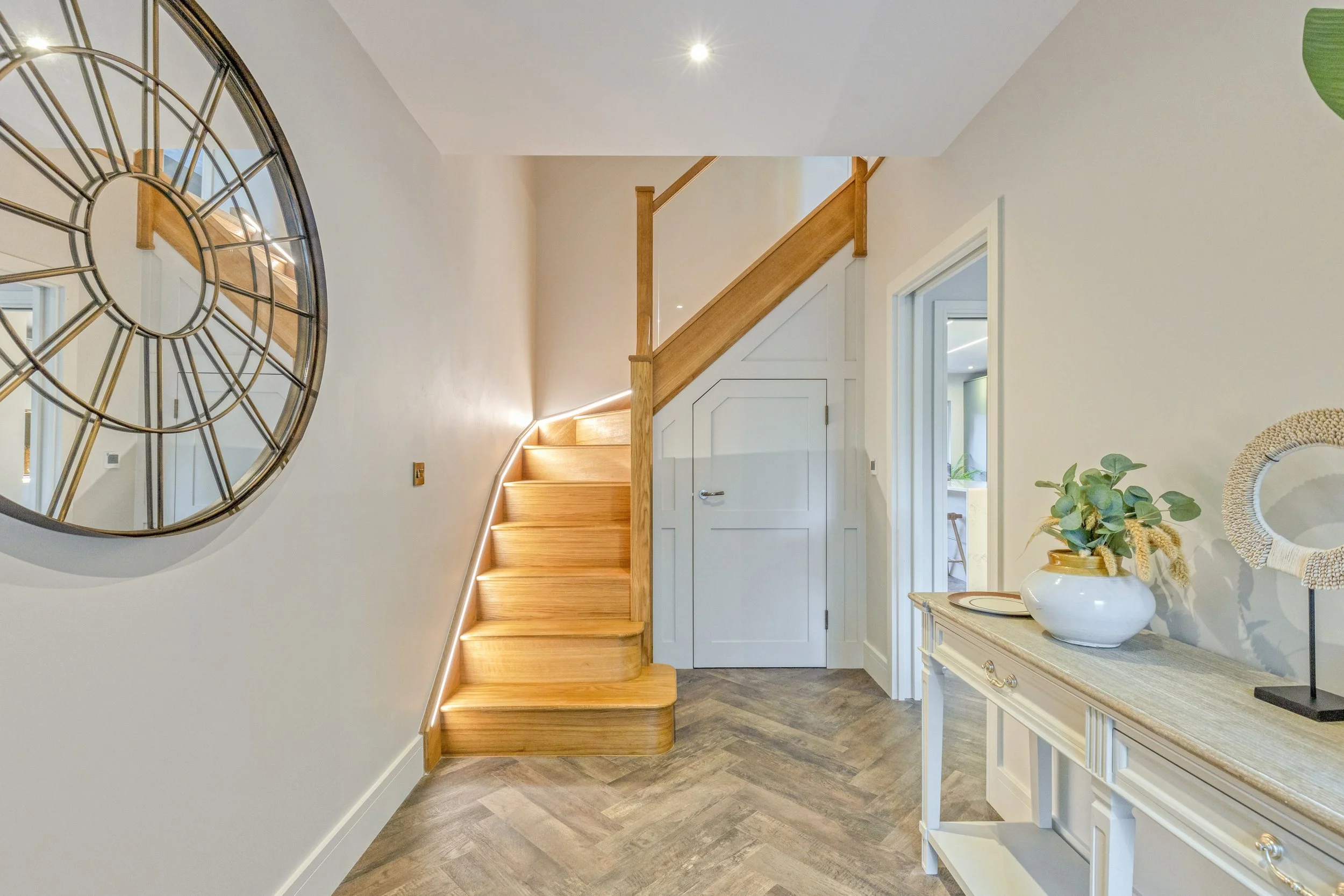 Entrance hall with herringbone flooring, oak staircase and LED lighting.
