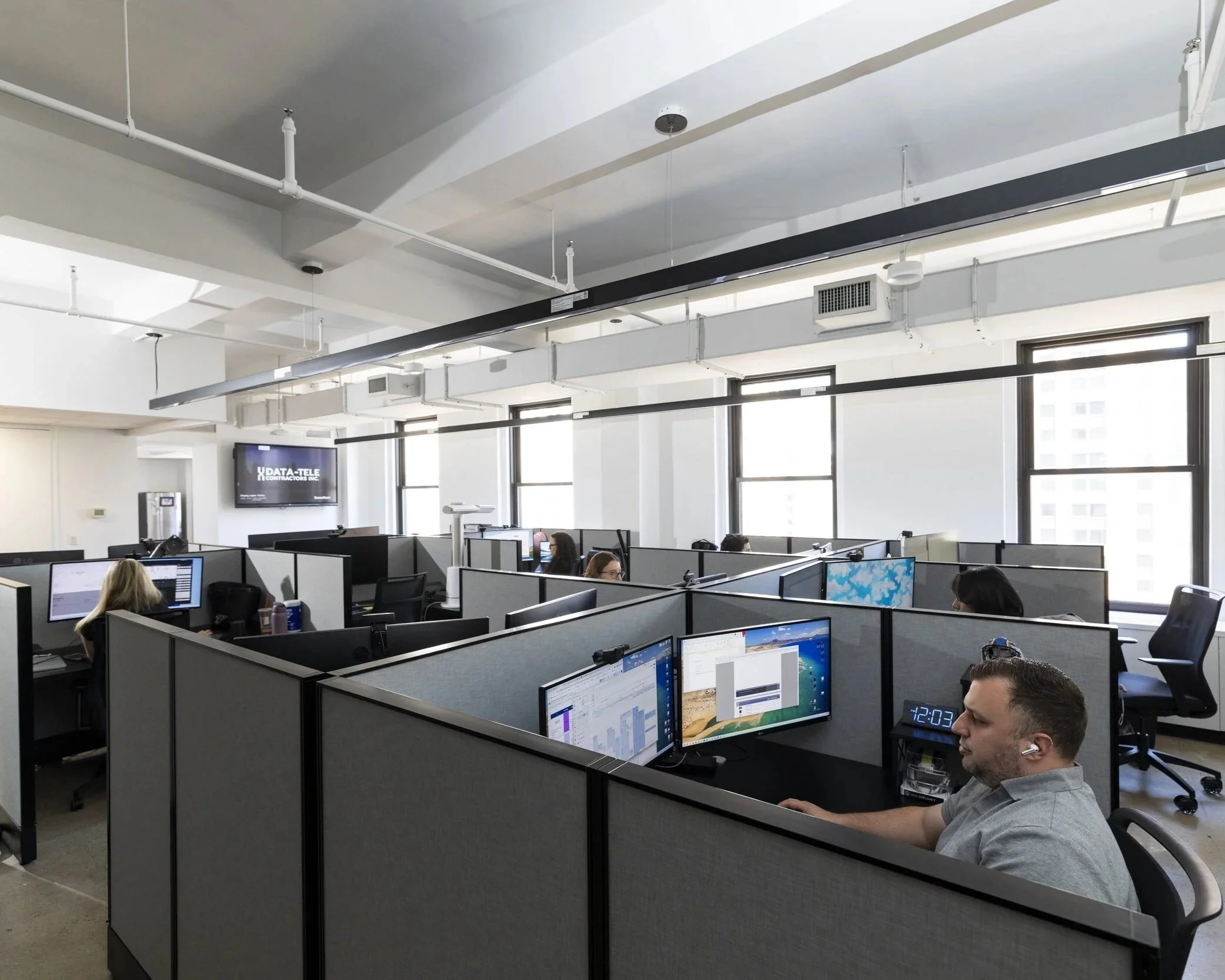 View of office space with grey cubicles and people working at computers