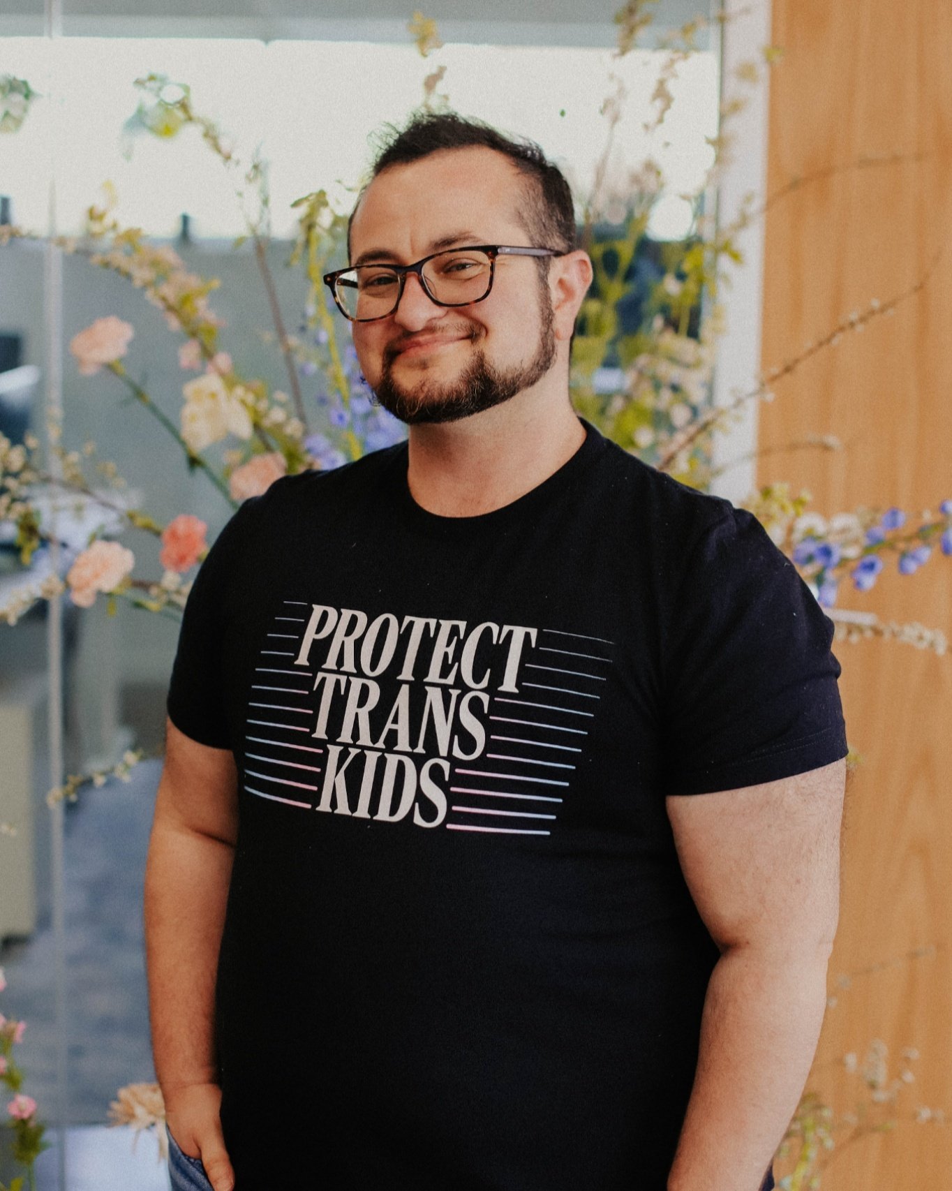 It's forever and always protect trans kids.

Photo by Jessi Chapman in front of The Wild Mother Floral at Freedom Oklahoma's 2024 Give Trans Folks Our Flowers While We're Still Here event in OKC. T-shirt by softhand.

ID: photo of someone in a black 