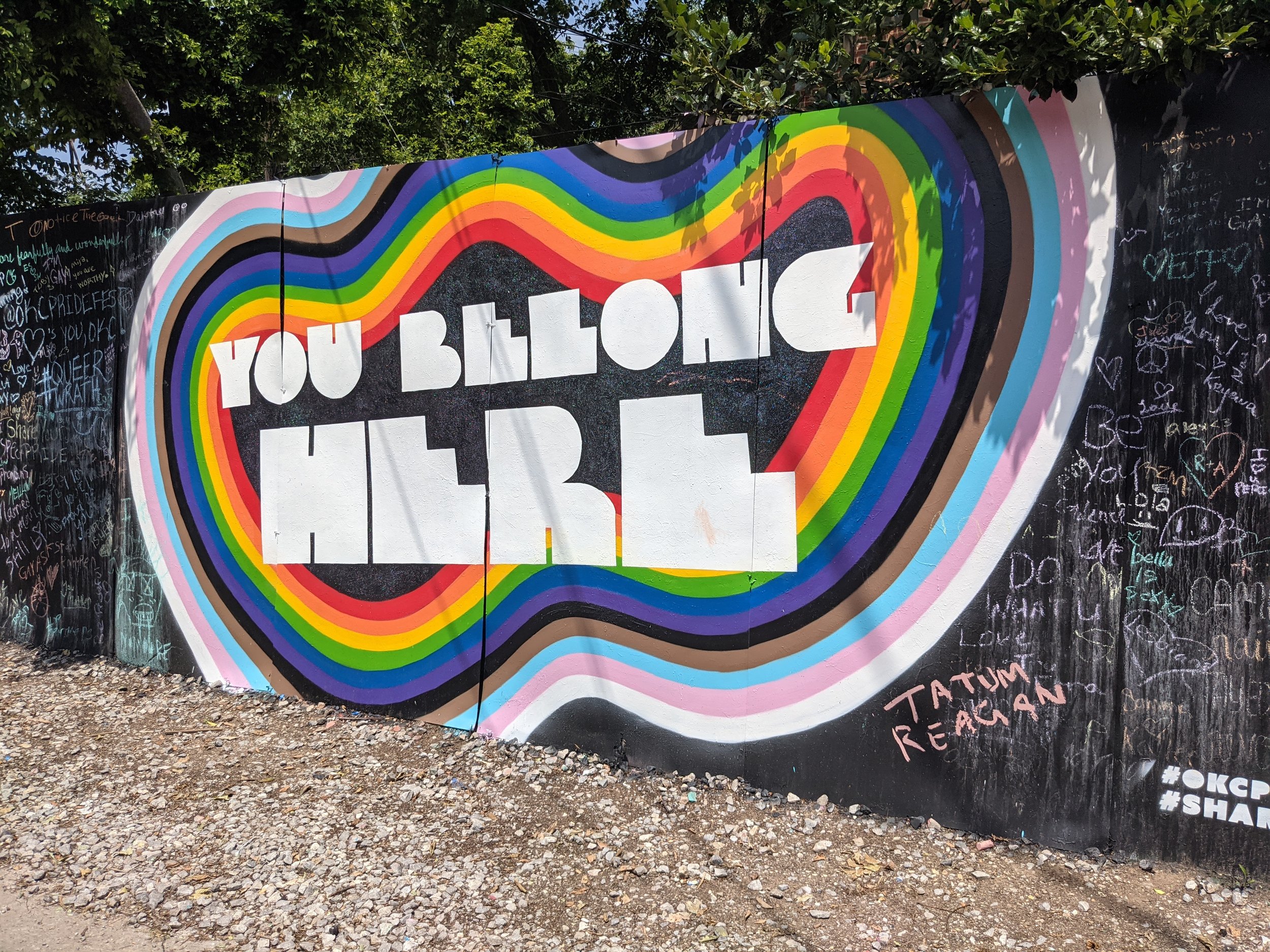 a mural in OKC at Plaza Walls with pride flag colors and text "You Belong Here"