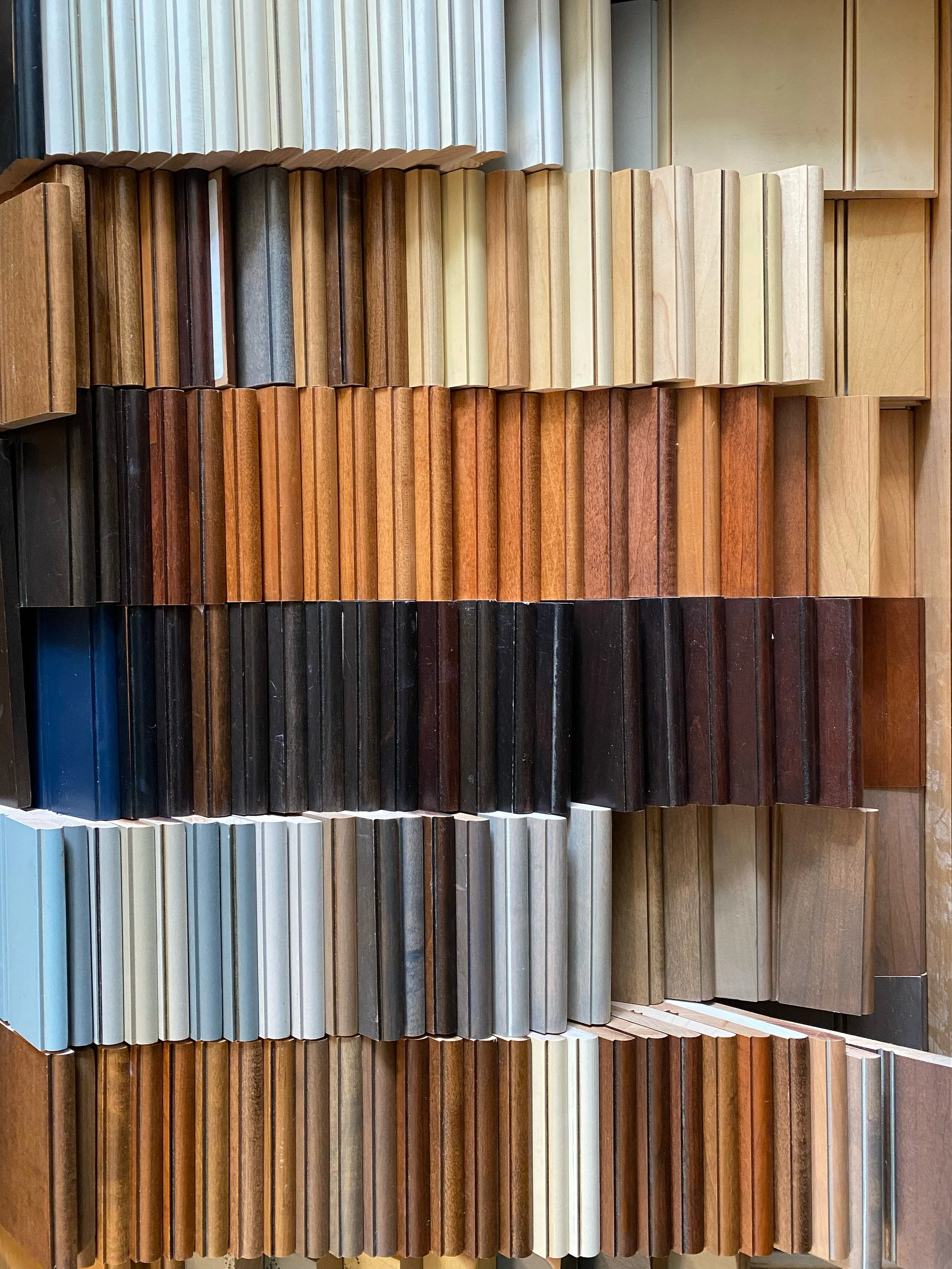 A display of woodworking samples arranged in rows, showcasing various wood finishes and colors.