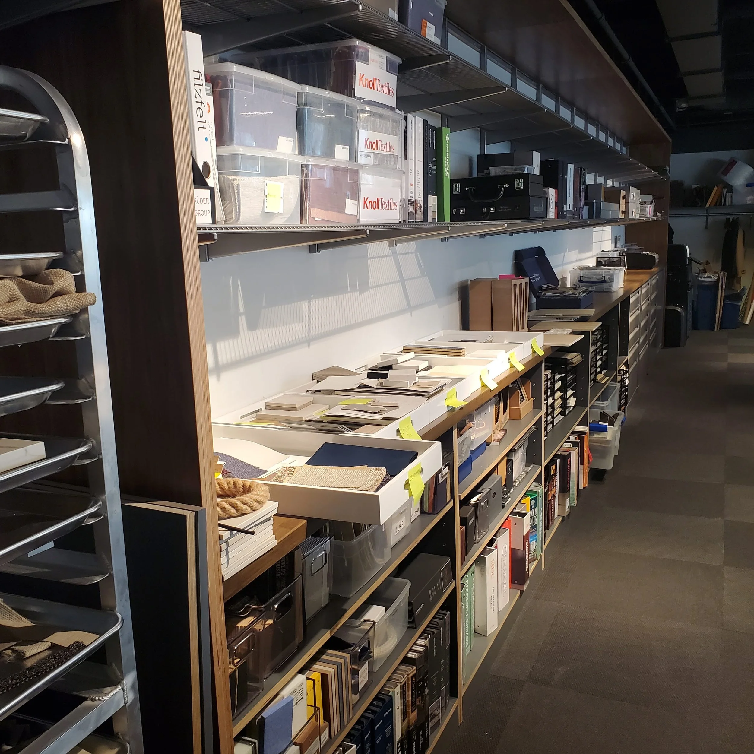 Bookshelf with various books and storage bins, some labeled 'Knoll Textiles' and 'Foley.'