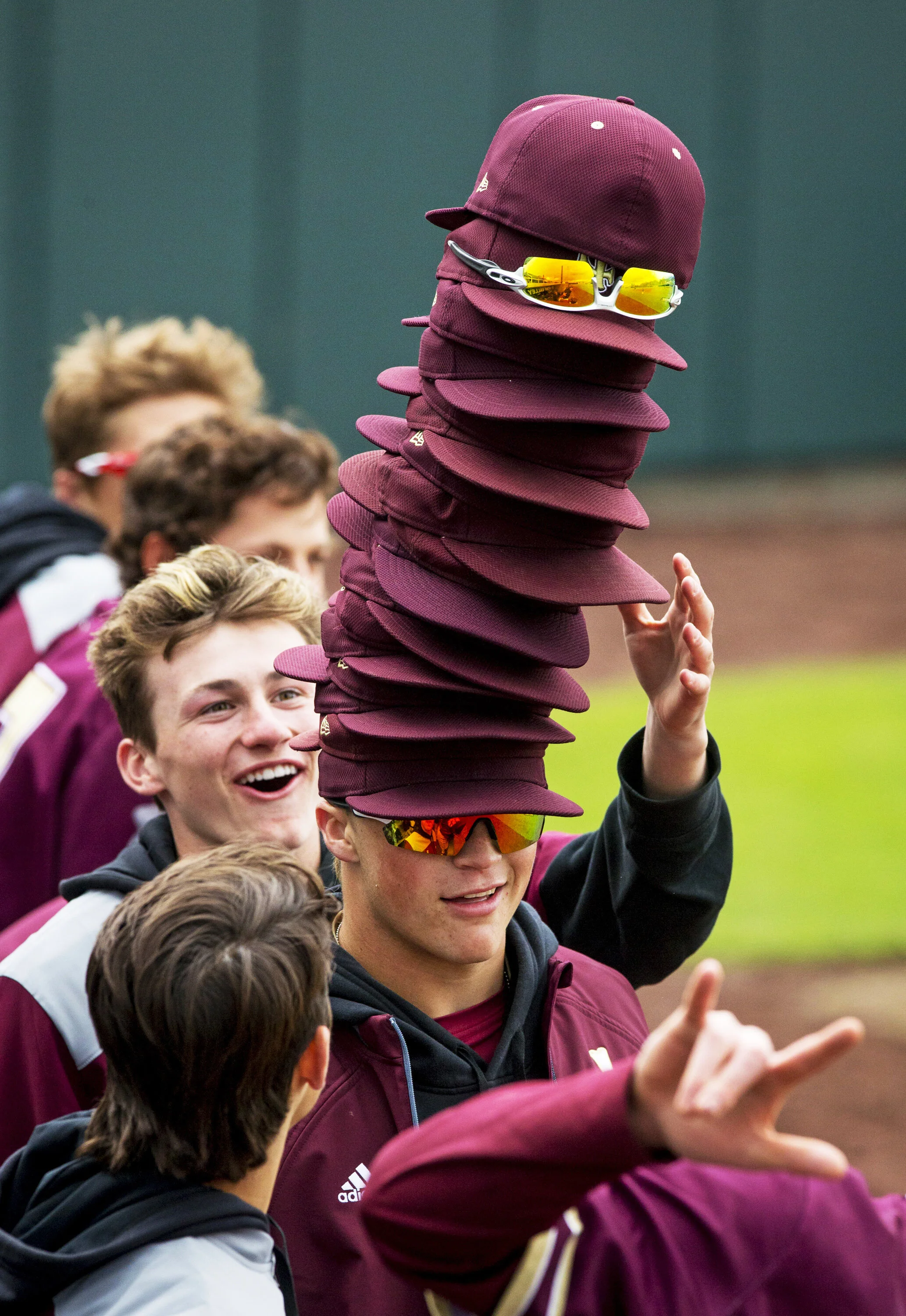 Lone Peak third baseman Cade Walker (2) tries to balance hats stacked on his head during an elimination-bracket semifinal game in the UHSAA 6A Baseball State Tournament between the Lone Peak Knights and the Syracuse Titans held Friday, May 24, 2019, 