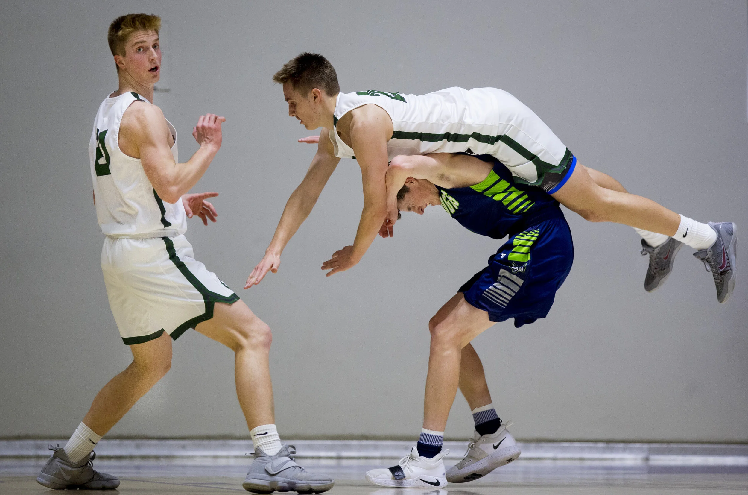 Olympus forward Jackson Frank (20) falls over Timpanogos guard Trey Anderson (5) after they both went for a rebound during a quarterfinal game between the Timpanogos Timberwolves and the Olympus Titans in the UHSAA 5A Boys Basketball State Tournament