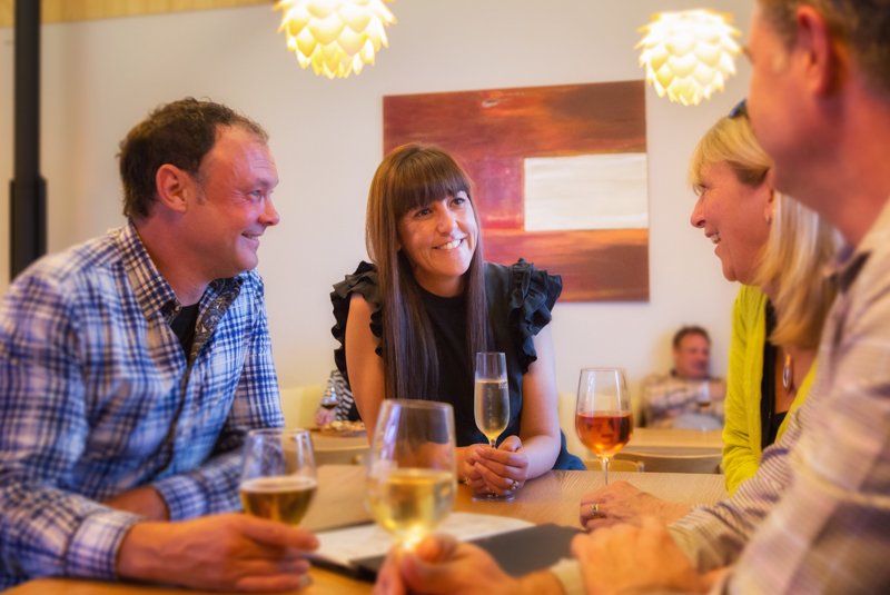 Smiling couple drinking wine with their friends