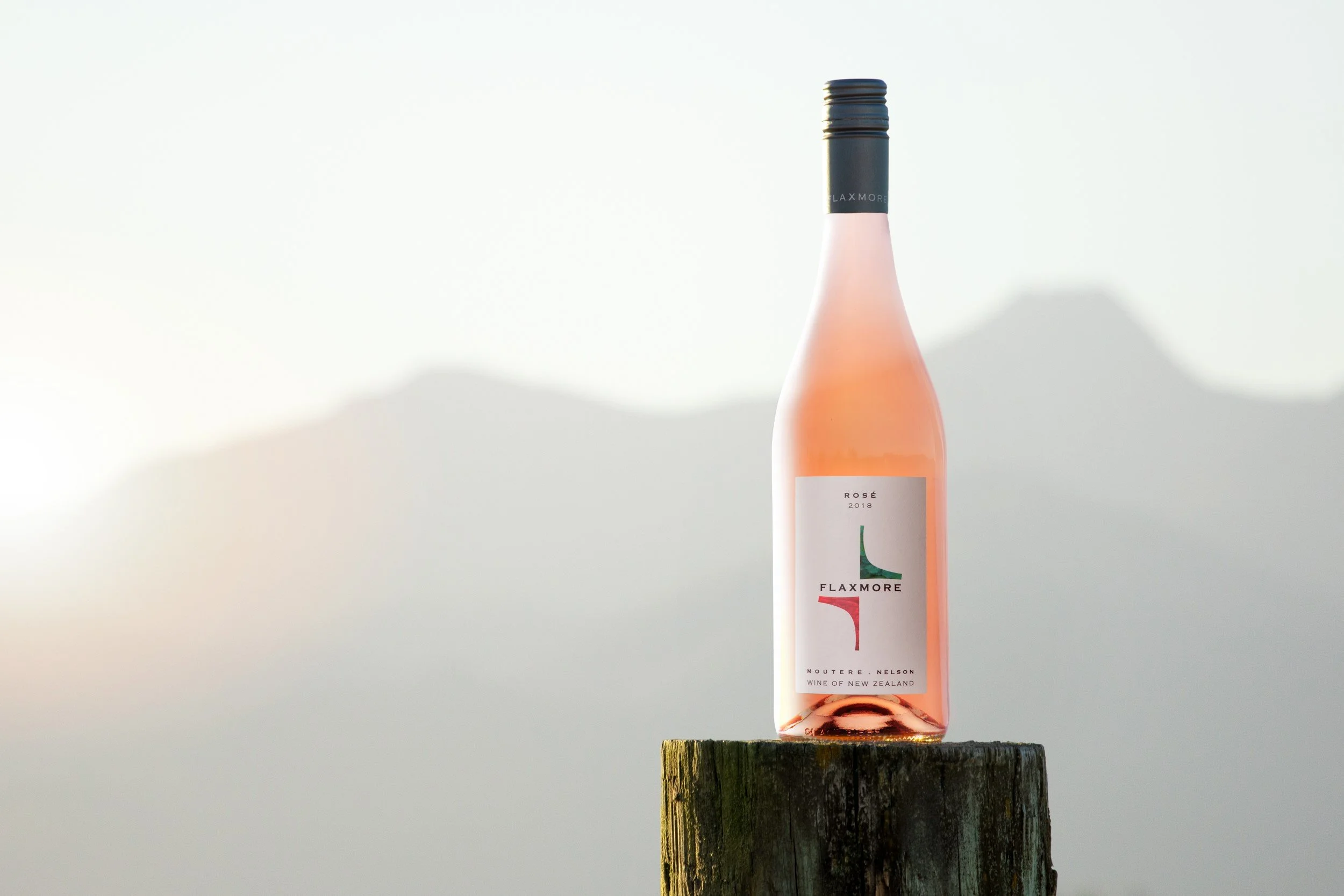 Bottle of Rose wine on fence post with mountains in distance