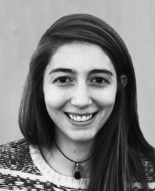 A young woman with light skin, brown hair, wearing a shirt with patterns