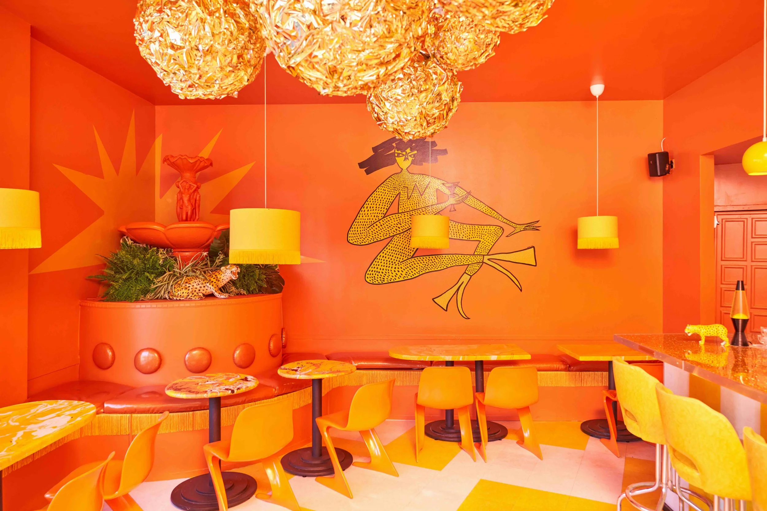 The Orange room at Shuggie's--a vibrant tangerine orange space with sparkly mylar disco balls and yellow crackle diner seats. Also featuring a big fountain and drinking lady mural.