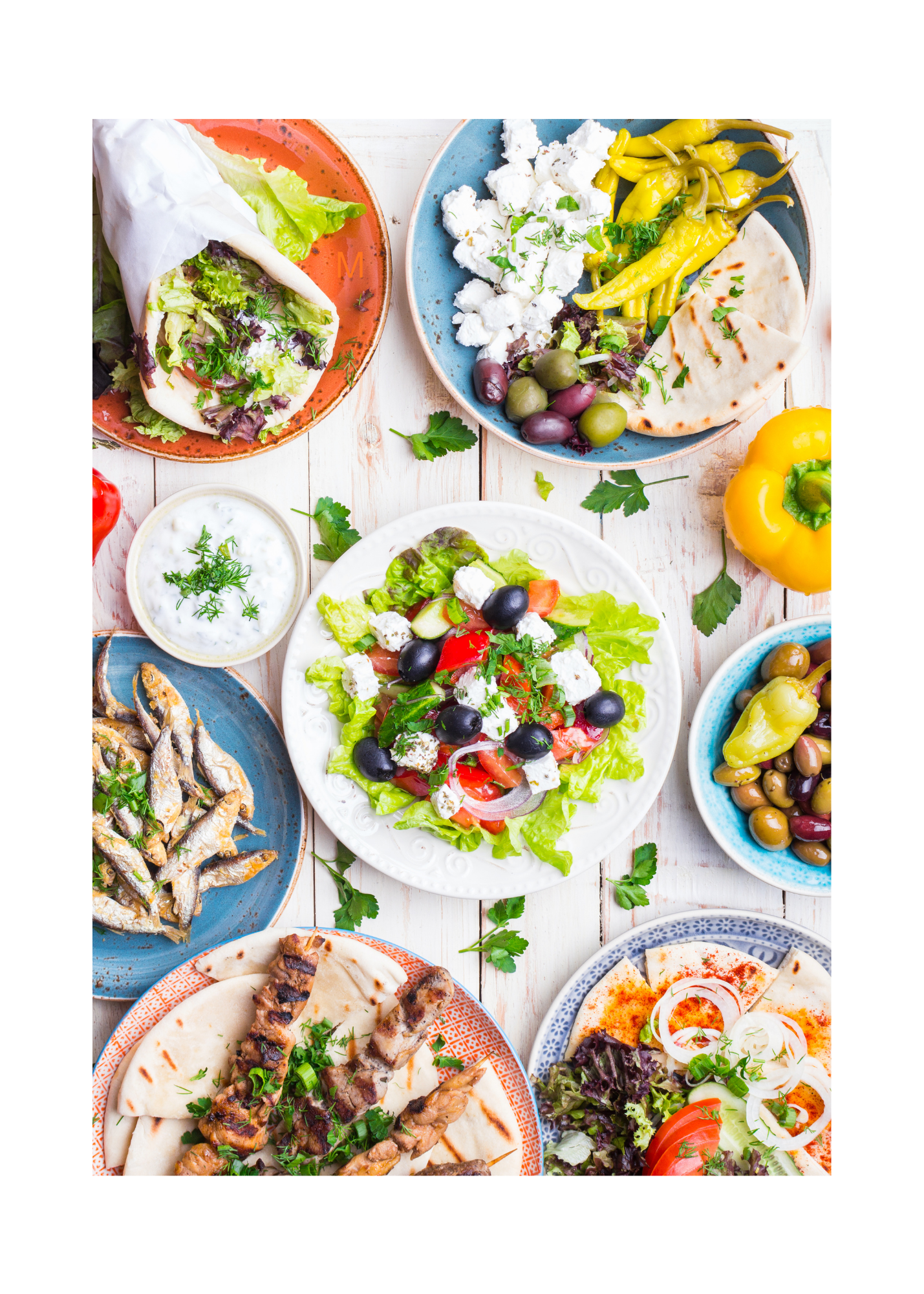 Mediterranean-style meal spread with Greek salad, pita, olives, and grilled protein