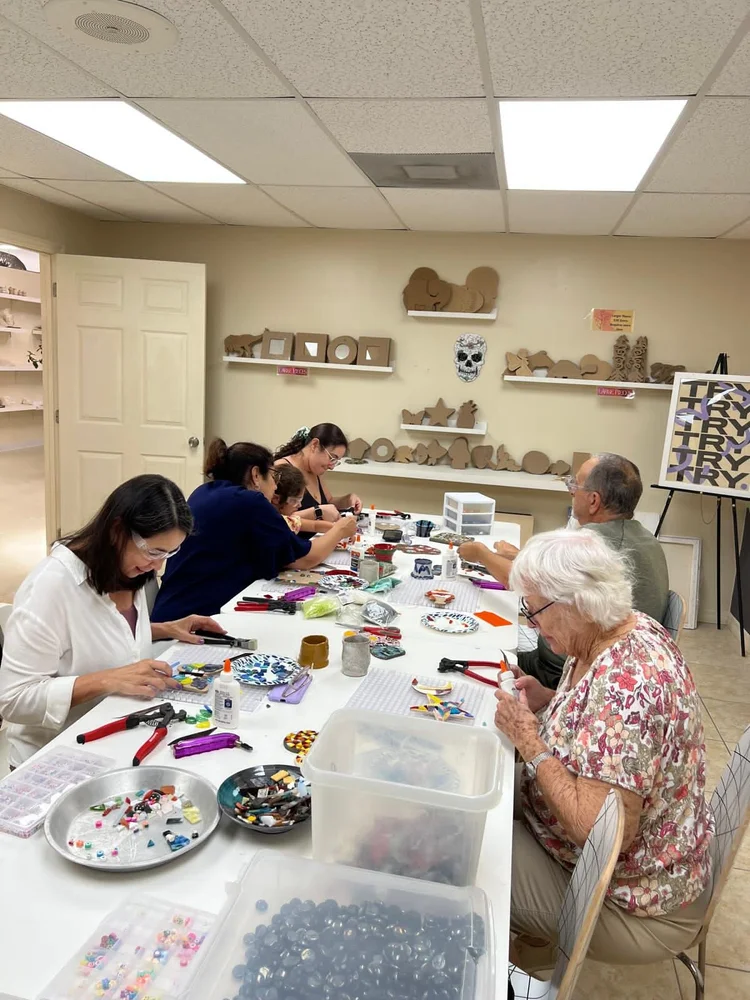 Adults working on mosaics around a long table at Gasper Arts