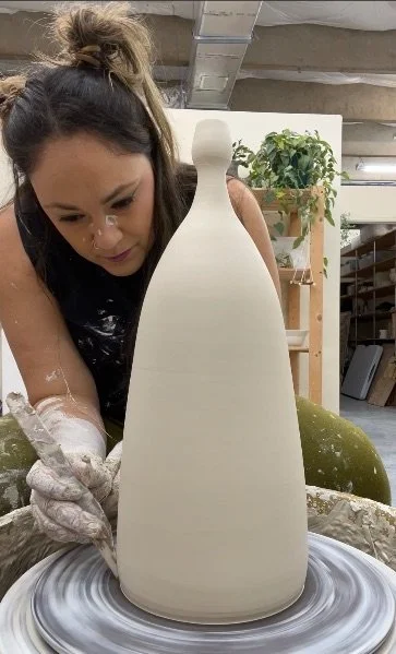 A potter shaping a tall vase form on the pottery wheel at Gasper Arts in Dania Beach