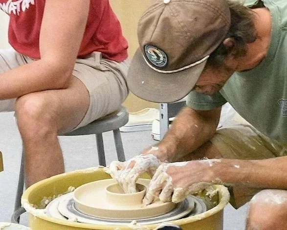 A potter centering clay on the wheel during an intermediate ceramics workshop at Gasper Arts