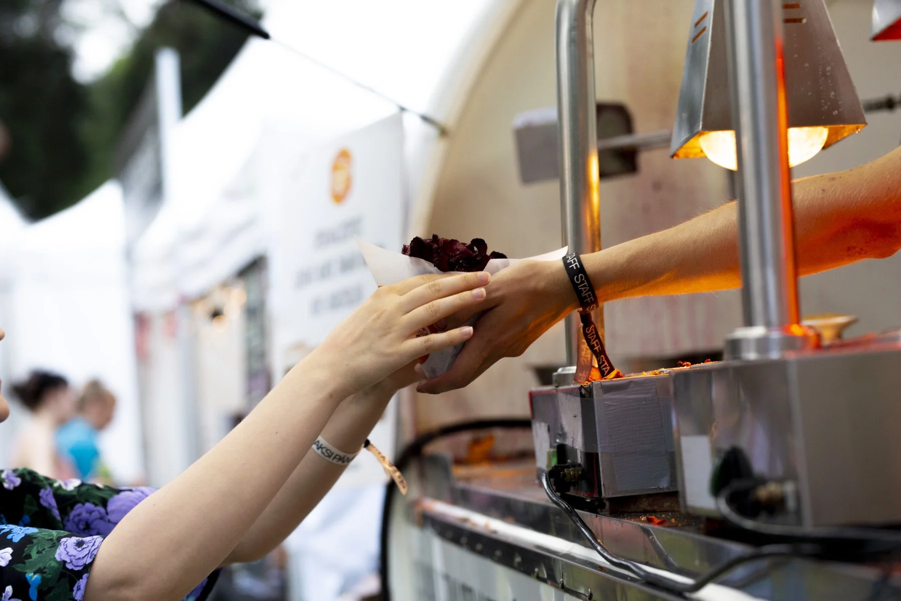 Käsi antaa henkilölle annoksen sipsikojusta myyntitapahtumassa.