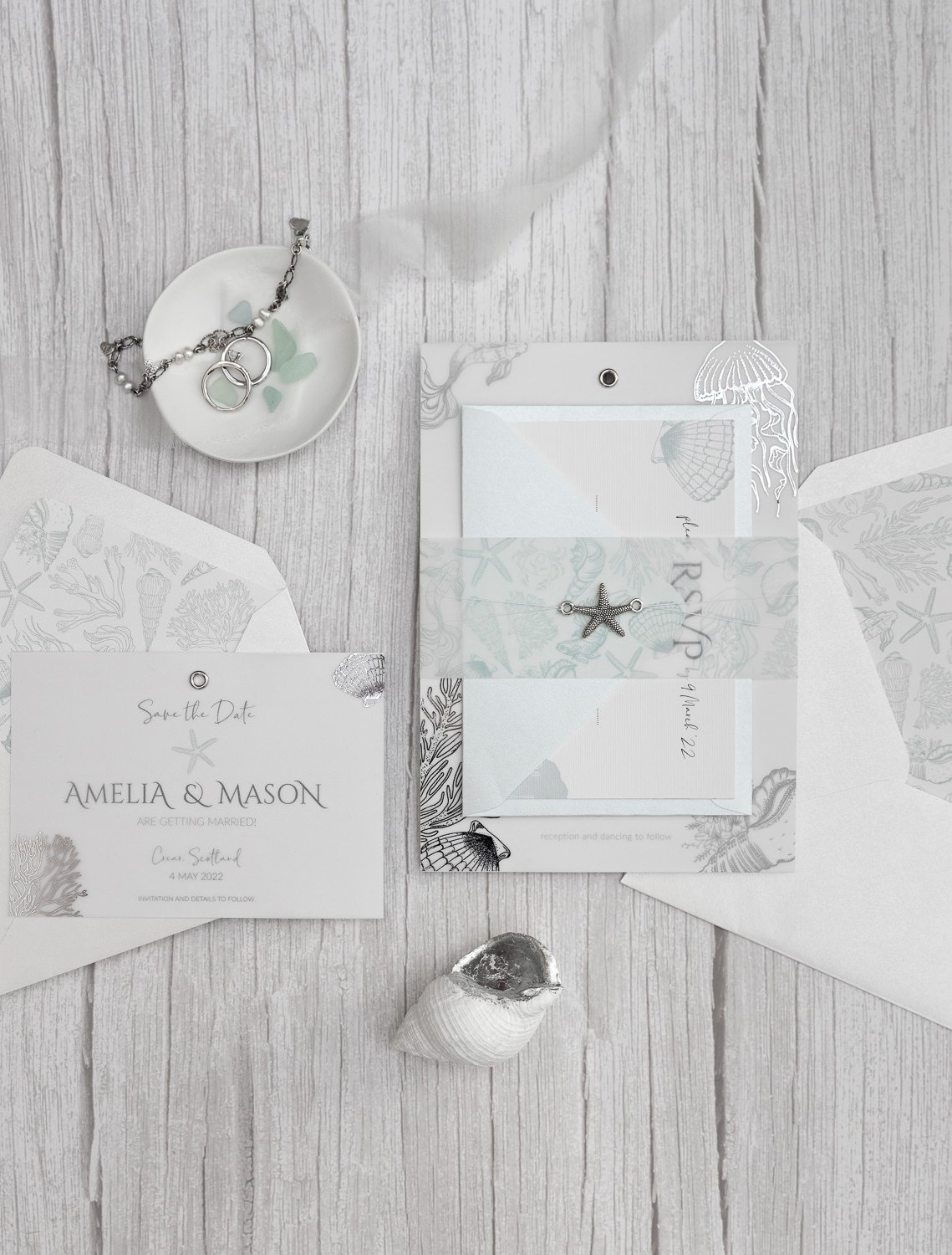 Beachcomber Sea Spray Charmed Invite™ with silver starfish charm, sea illustrations vellum belly wrap, and 'Aquamarine' RSVP envelope