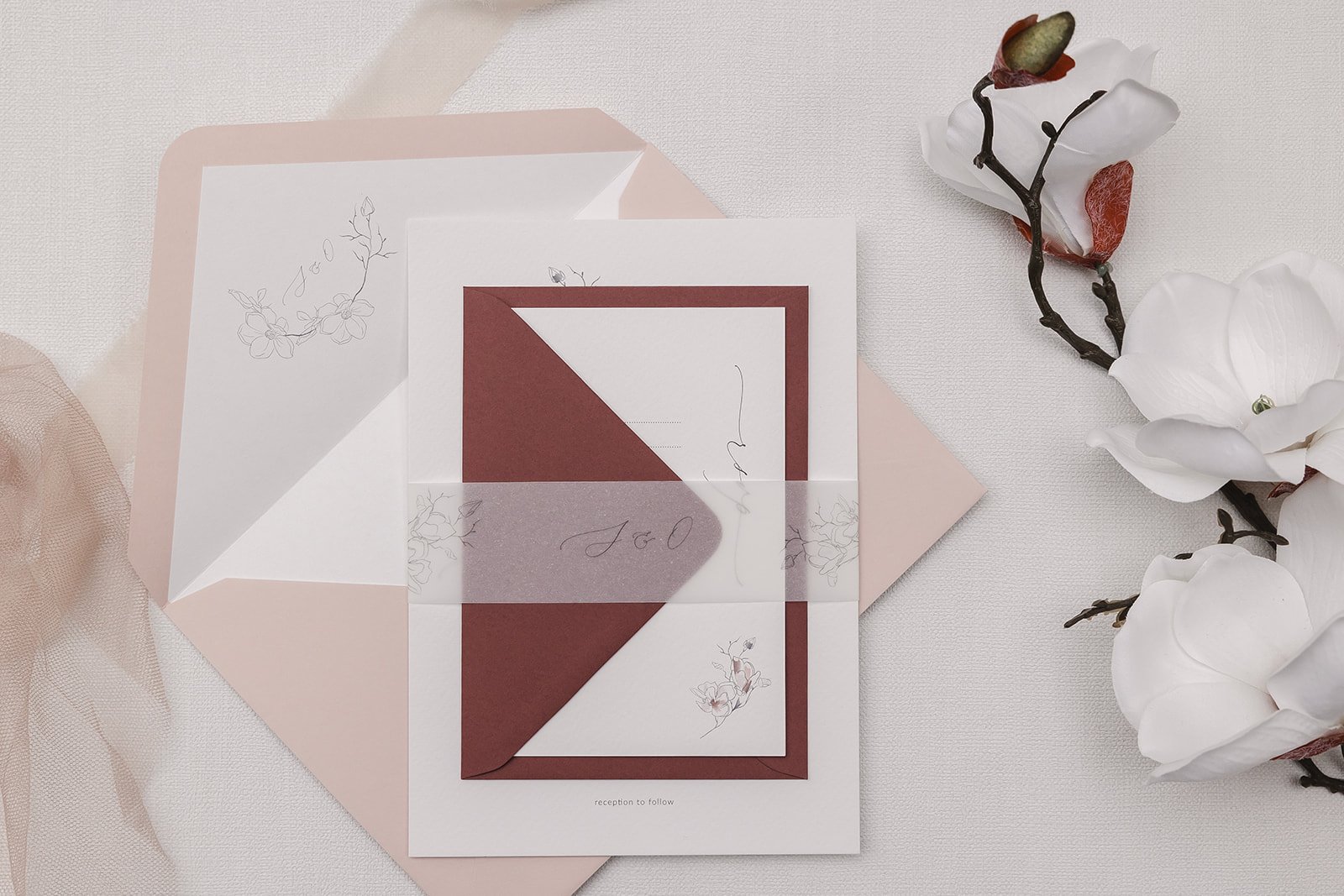 Day invite set with main envelope in Blush with white liner, and RSVP envelope in Rosebud, bound with illustrated monogrammed vellum belly band