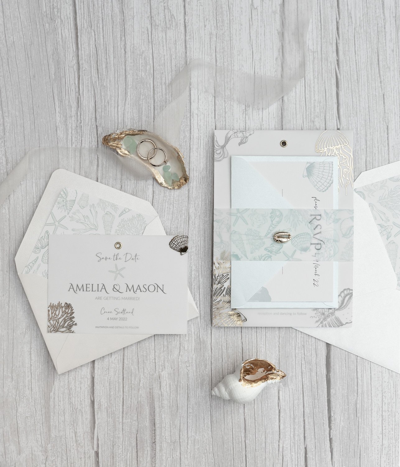 Beachcomber Sea Spray Charmed Invite™ with gold cowrie shell charm, gold-foiled vellum overlay, sea illustrations vellum belly wrap, and mix-and-match envelopes