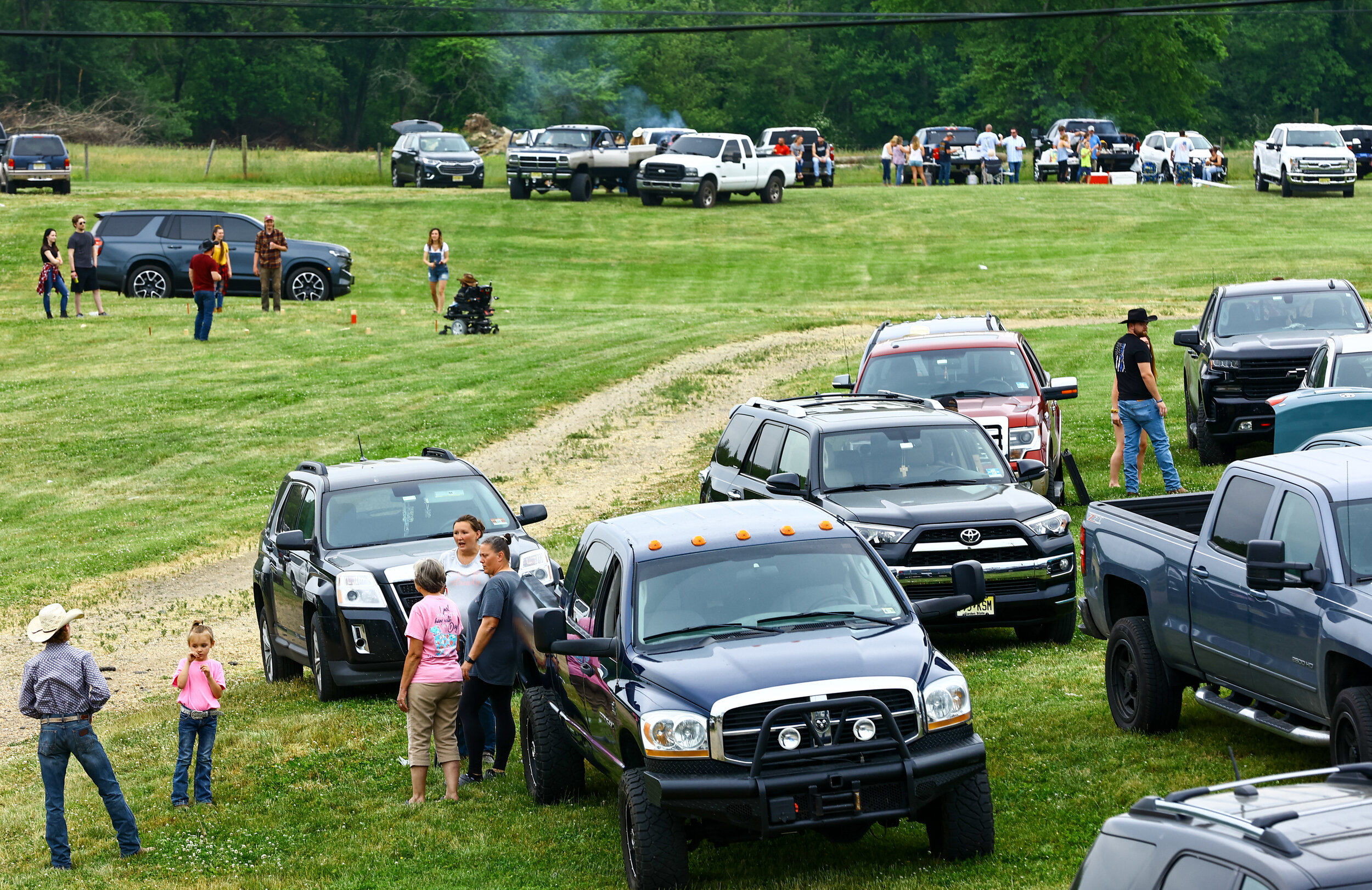 Spectators tailgate in a large field behind the rodeo arena in the hours leading up to start time. Country music, grilling, and beer drinking are prevalent with a noticably convivial atmosphere.