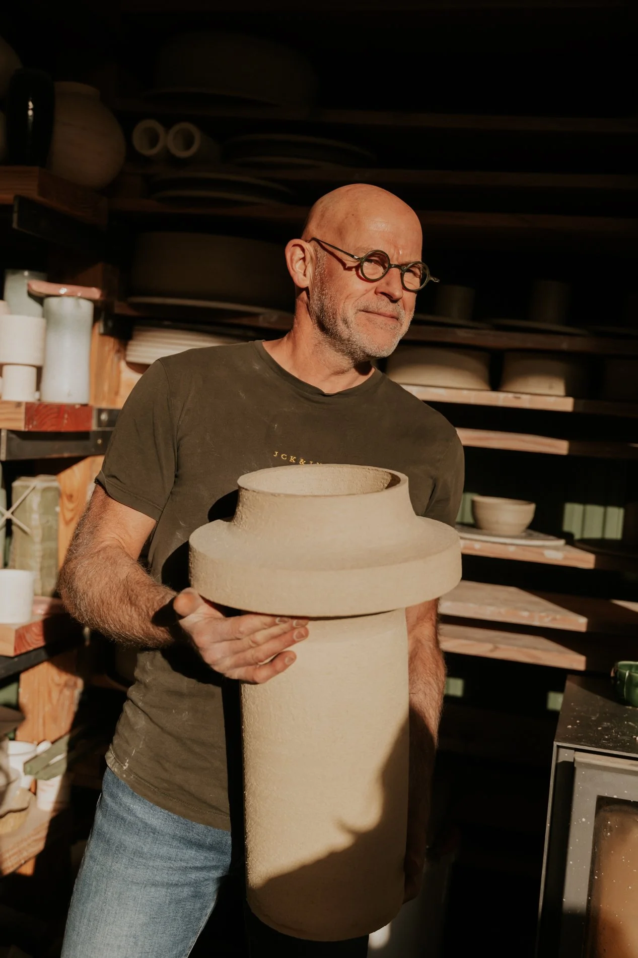 Pyotr Morf die zijn handgedraaide lamp toont in zijn atelier. 