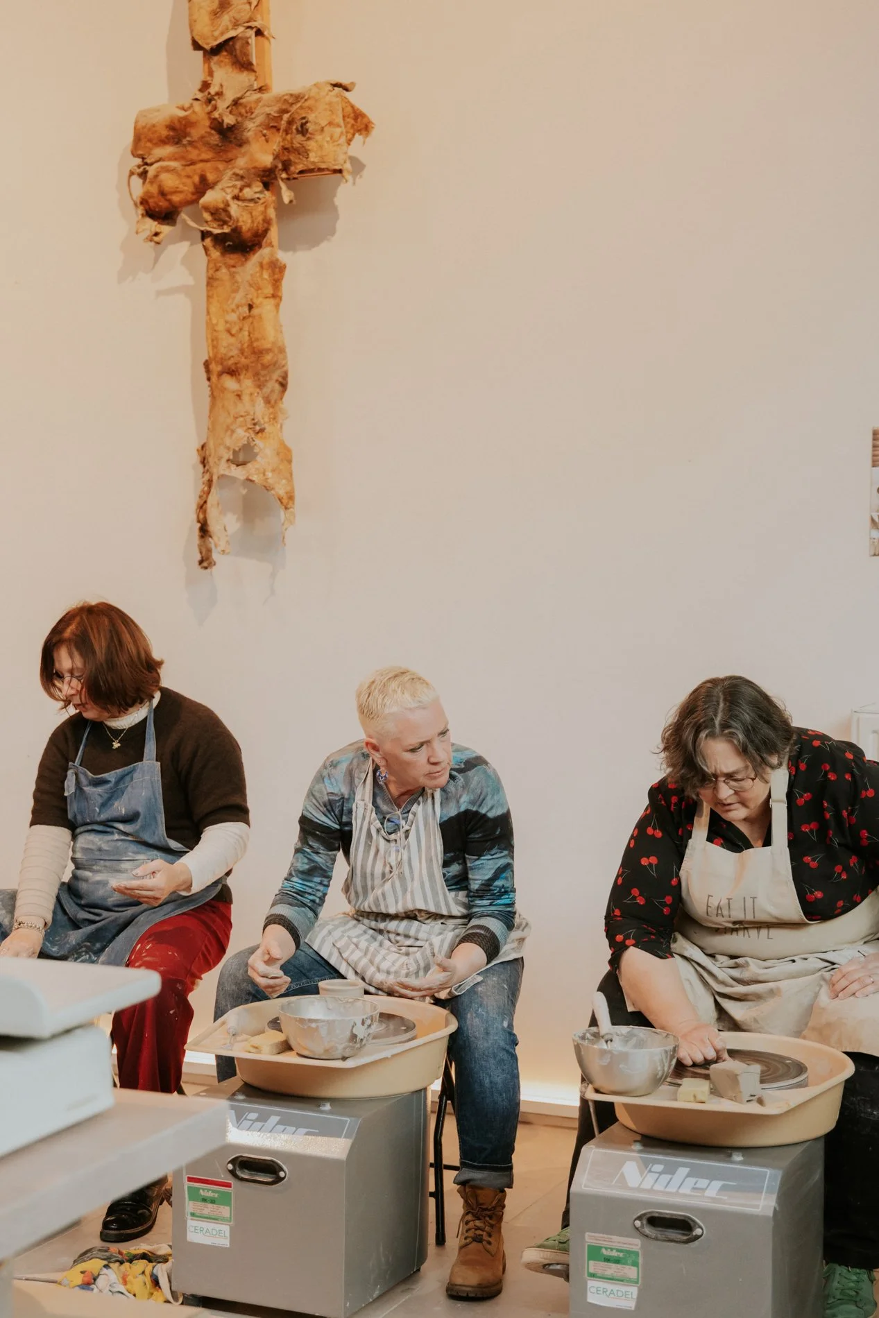 Moeders die een workshop pottendraaien volgen in een atelier.