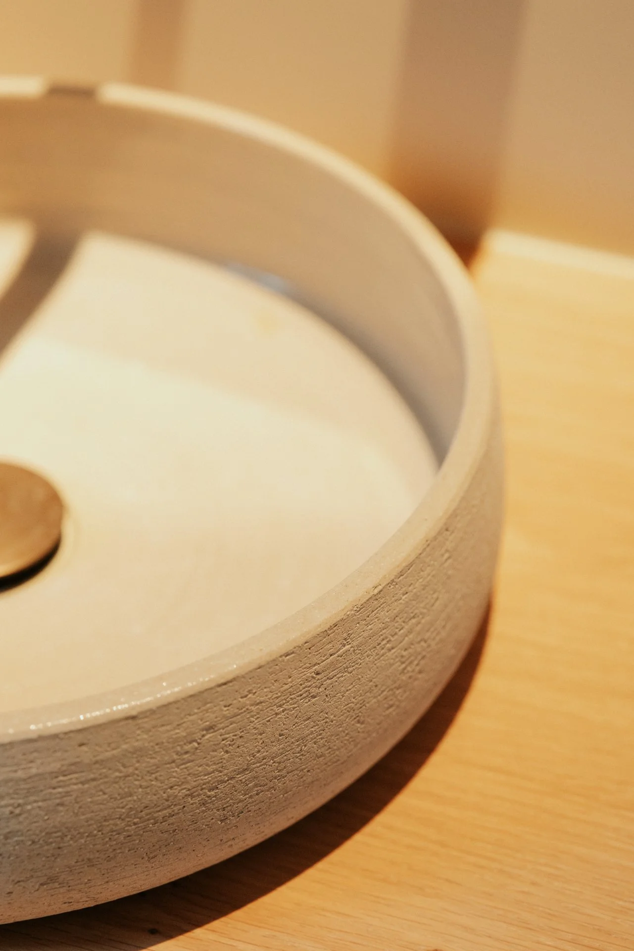Detail van een lavabo in keramiek op een houten tablet. 
