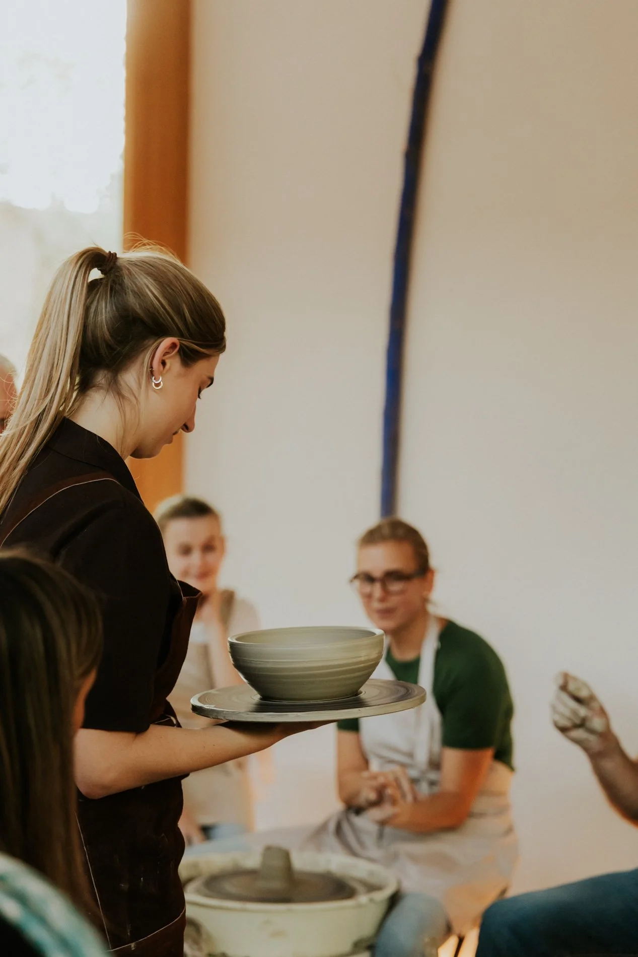 Vrouw die haar zelf gedraaide kom toont aan de andere kermisten in het atelier tijdens pottendraai workshop