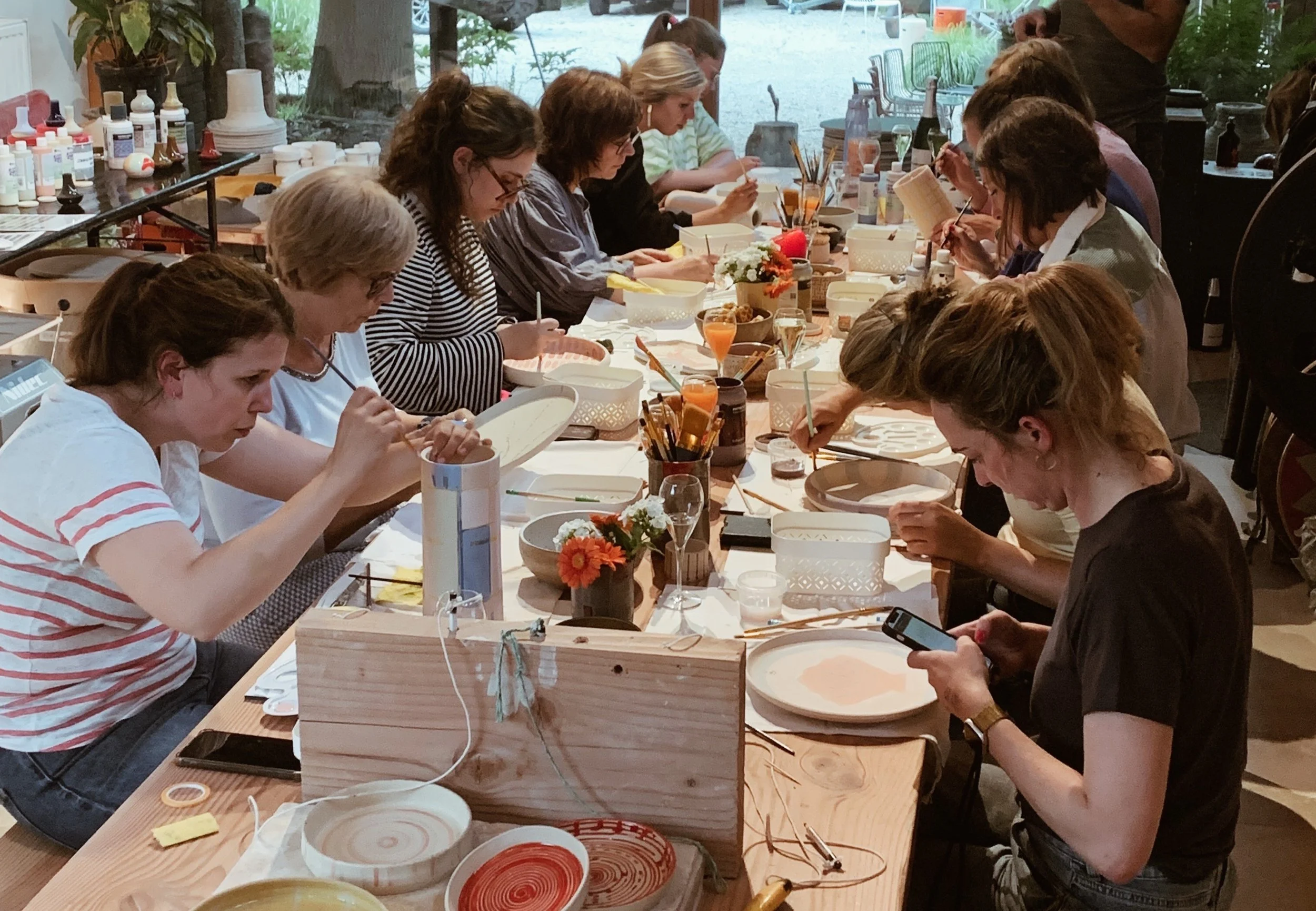 Groep vrouwen die bezig is met pottery painting workshop in een atelier.