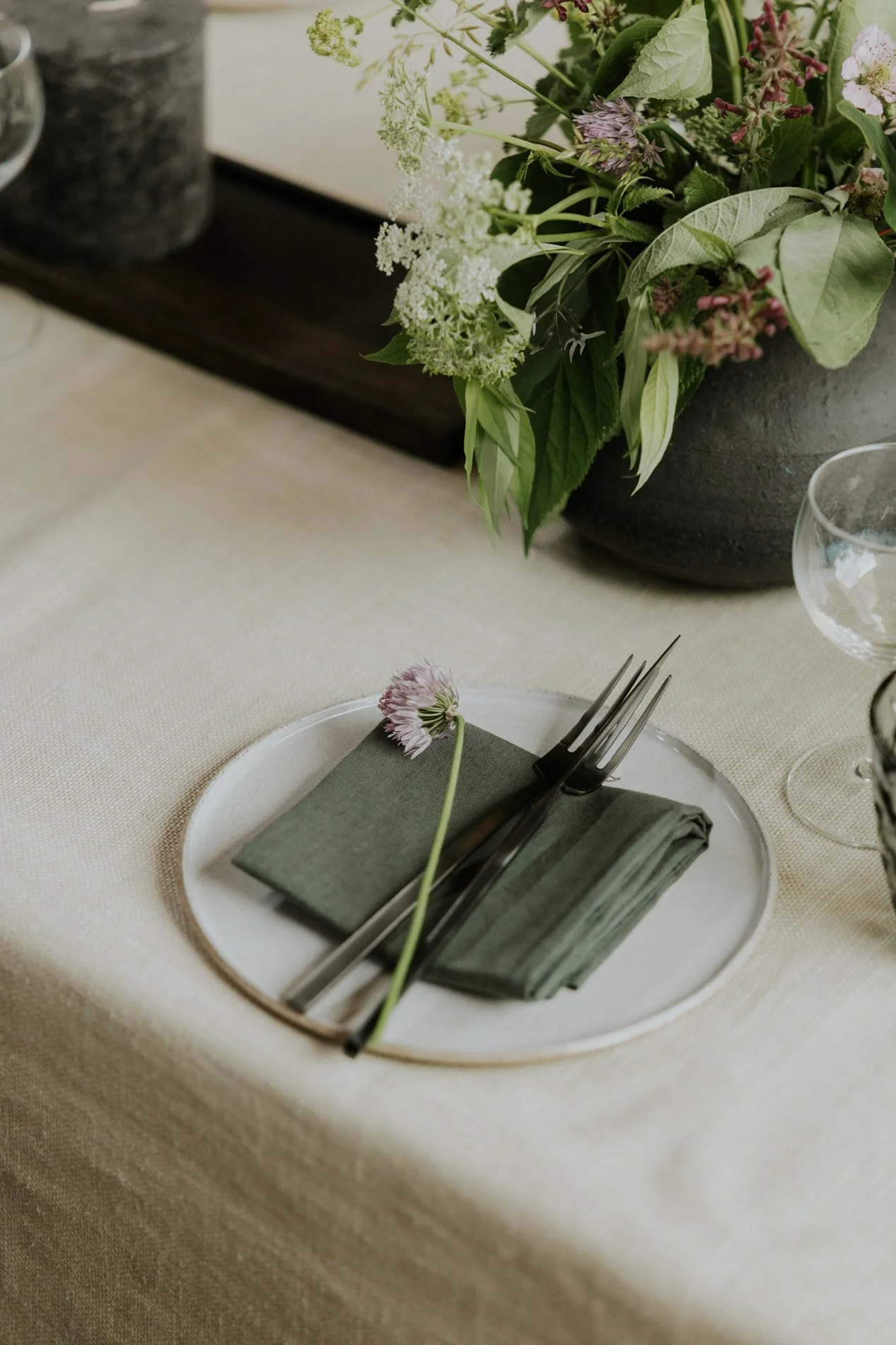Gedekte tafel met wit keramisch bord. Bloemen op de achtergrond.
