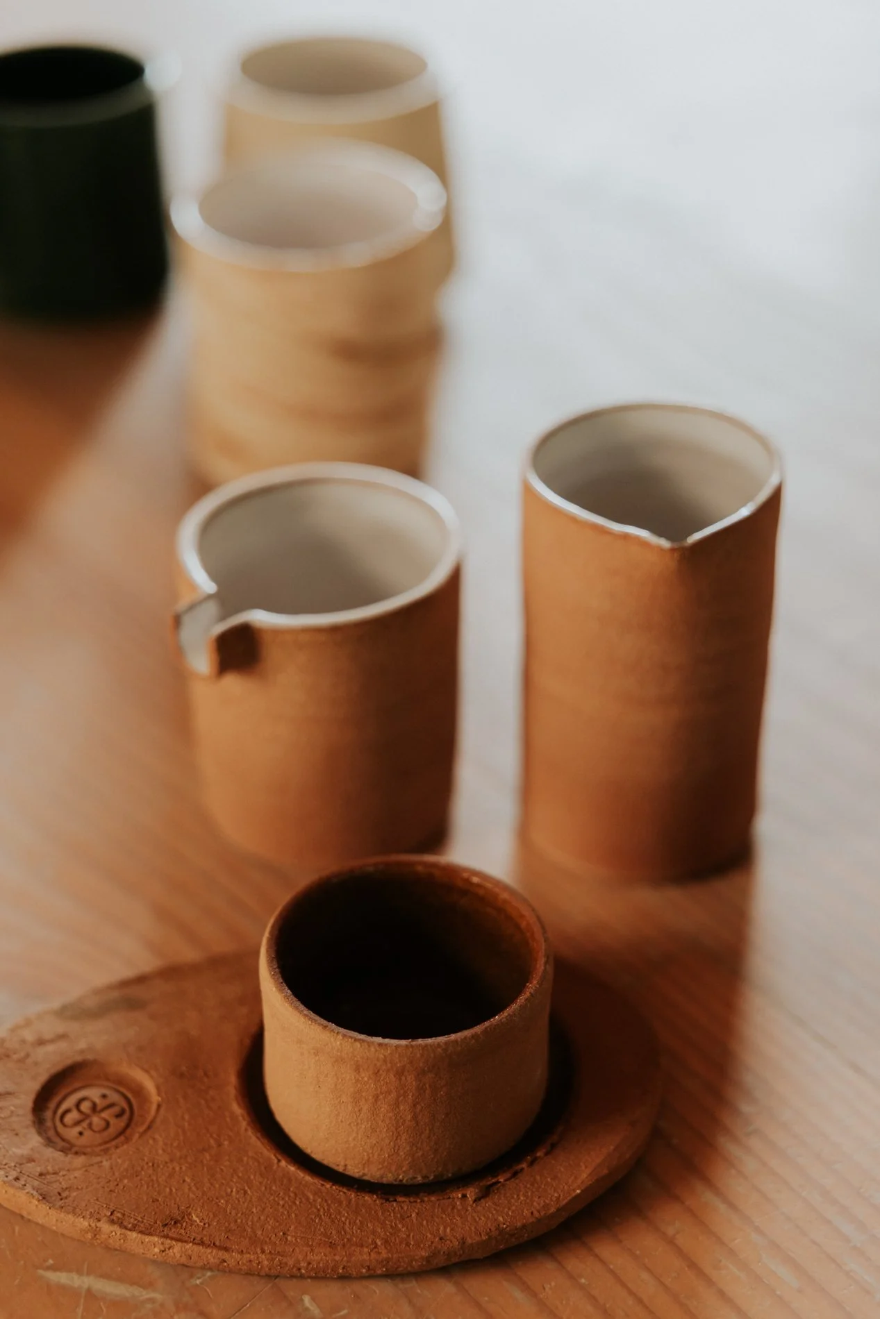 Kopjes in keramiek met vormen op een tafel in hout.