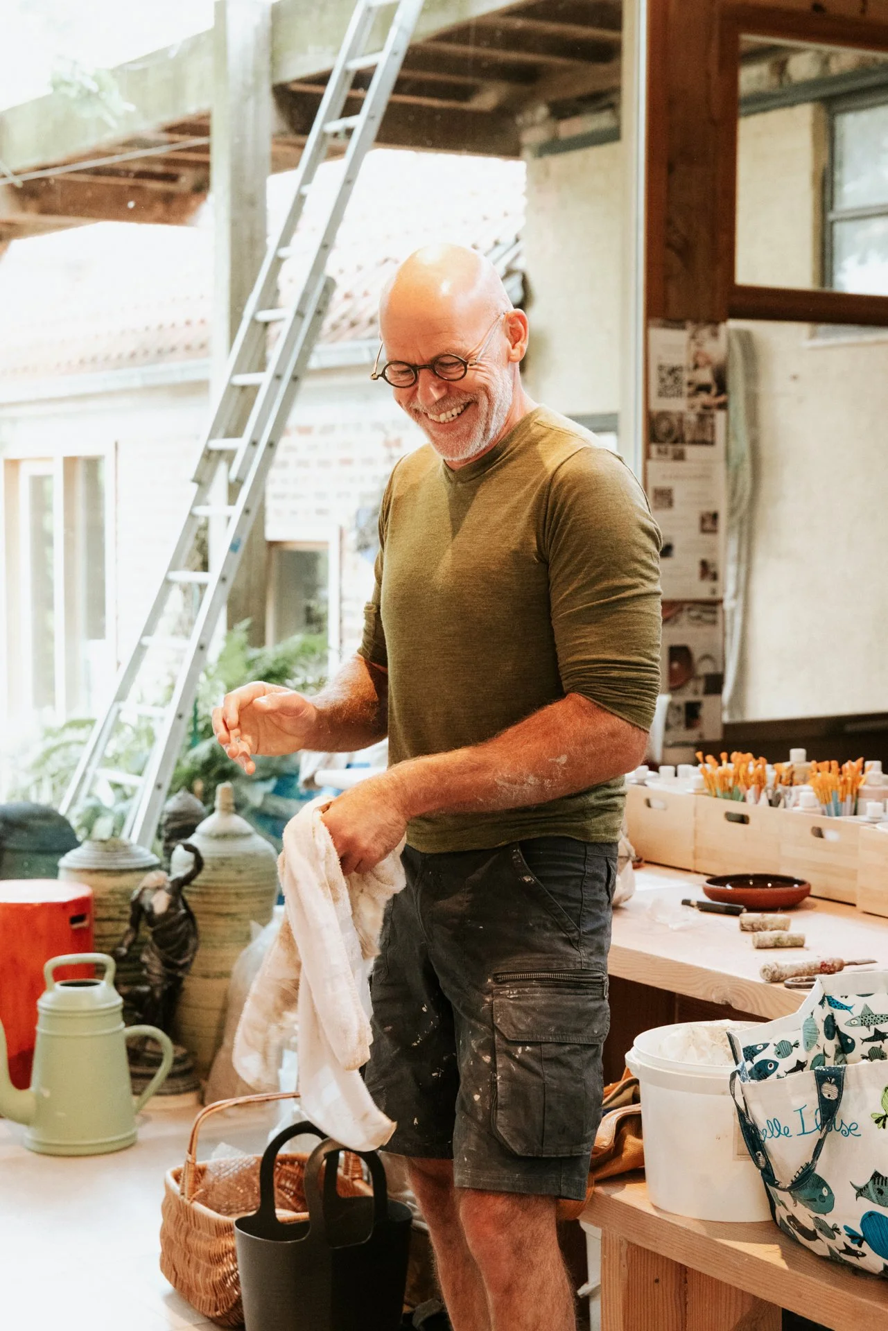 Pyotr Morf in zijn atelier die aan het lachen is, met een handdoek in zijn handen.  Atelier Pyotr Morf.
