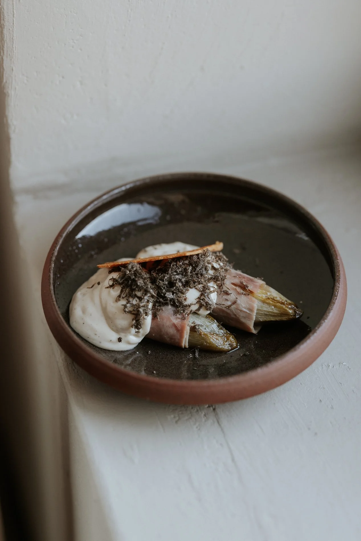Kommetje in keramiek op een vensterbank, mooi gepresenteerd eten in, vis met saus. Atelier Pyotr Morf