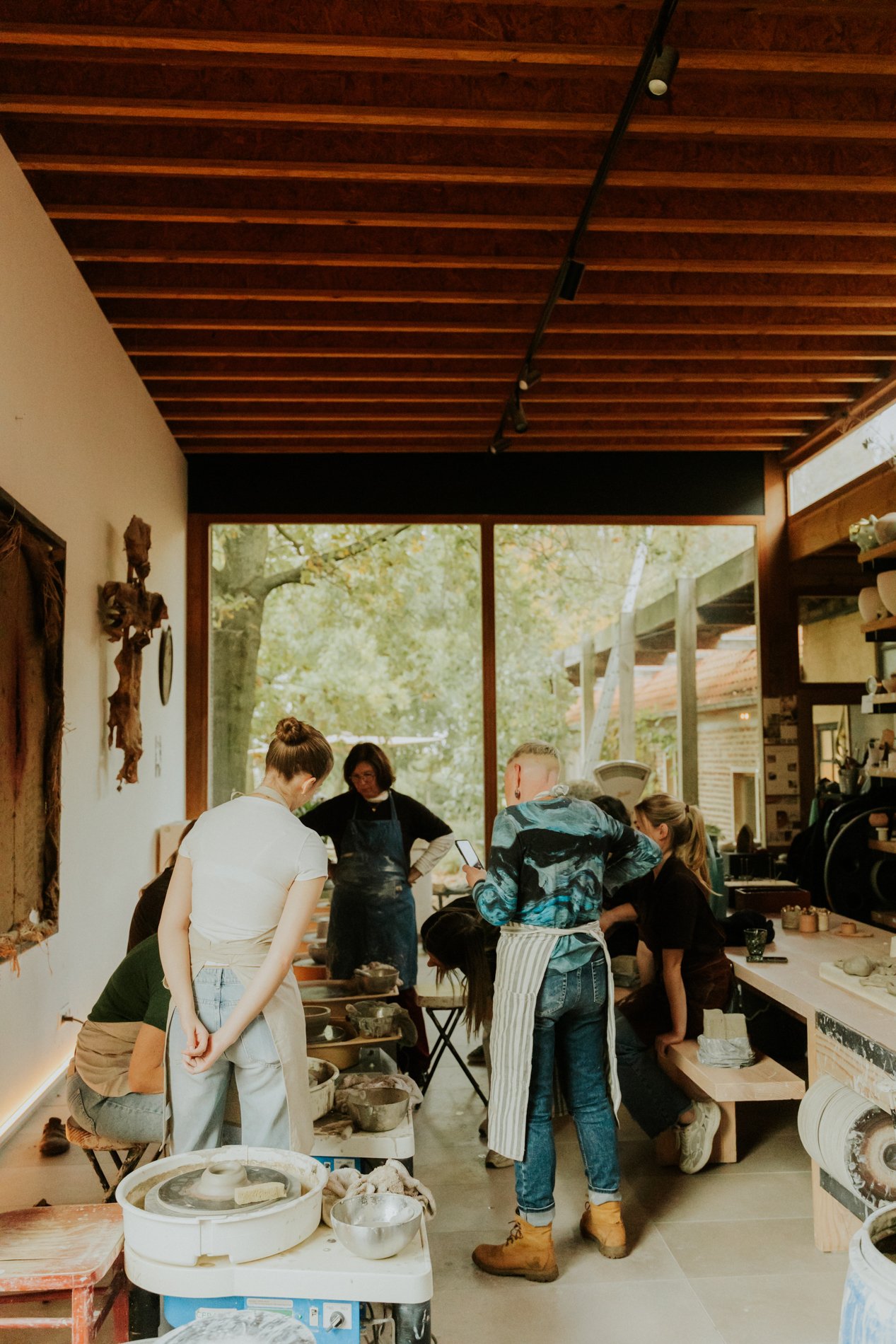 Groep cursisten die staan te kijken naar lesgever pottenbakken.