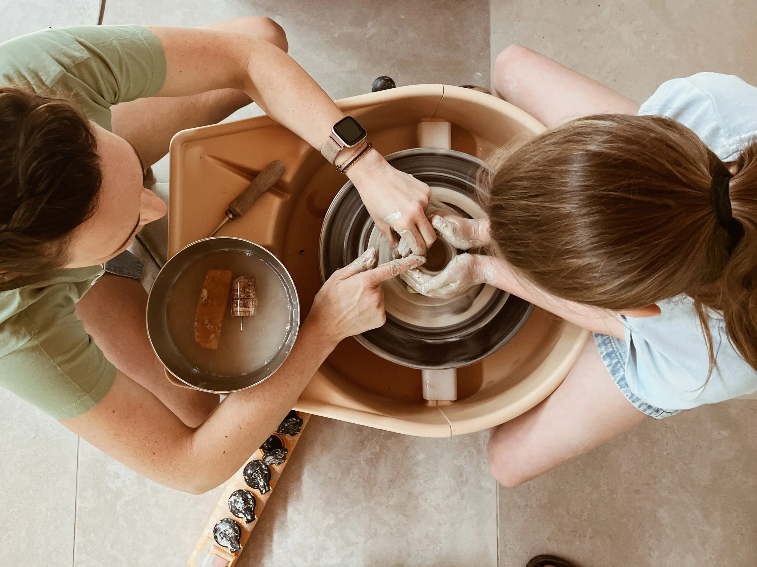 Hand die met spons water op klei brengt op draaitafel- Atelier pyotr morf