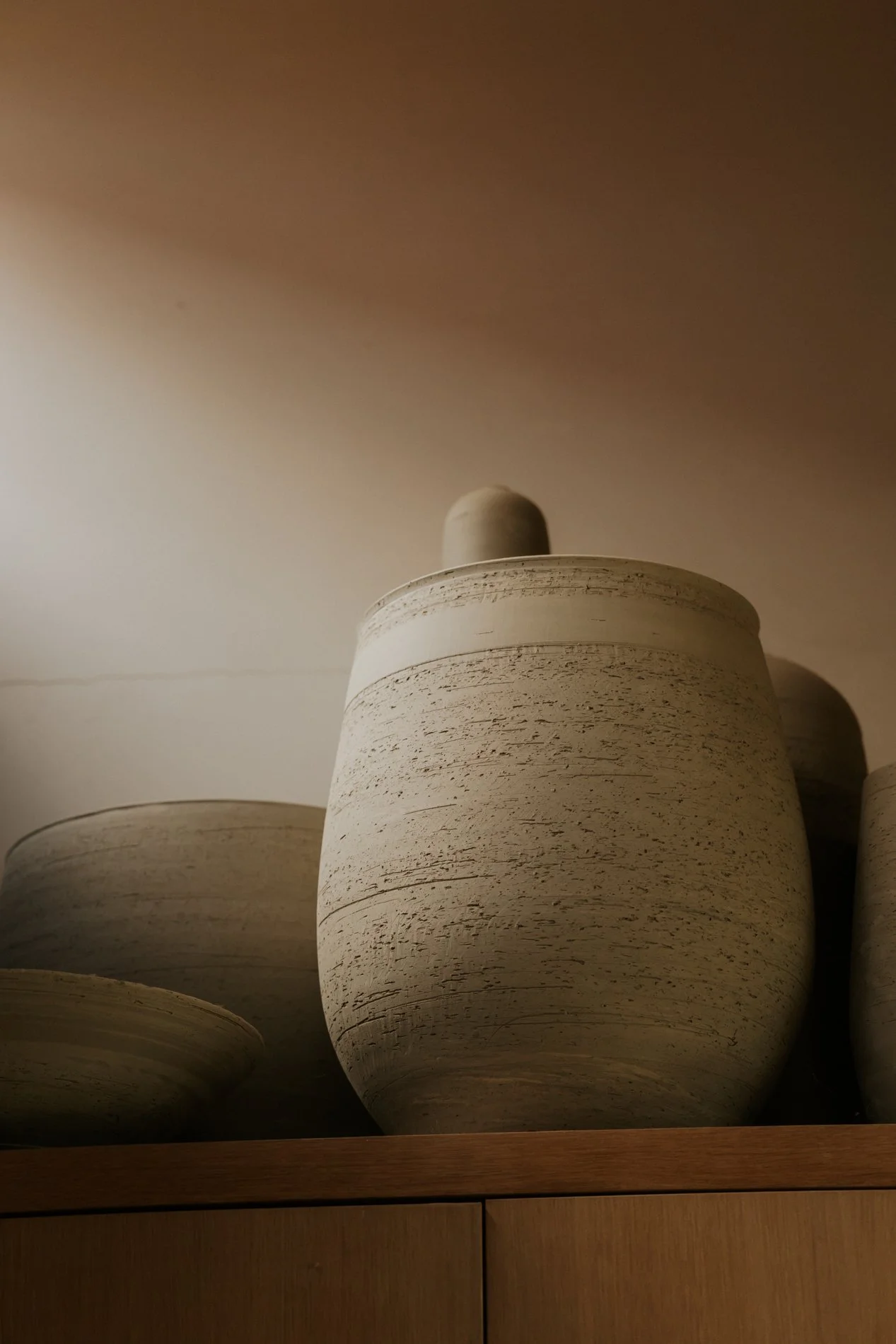 Groot formaat keramieken potten bovenop een kast in het atelier.