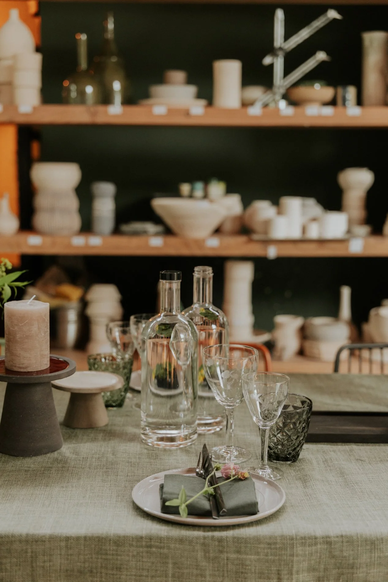Gedekte tafel in een atelier met keramiek op de achtergrond.