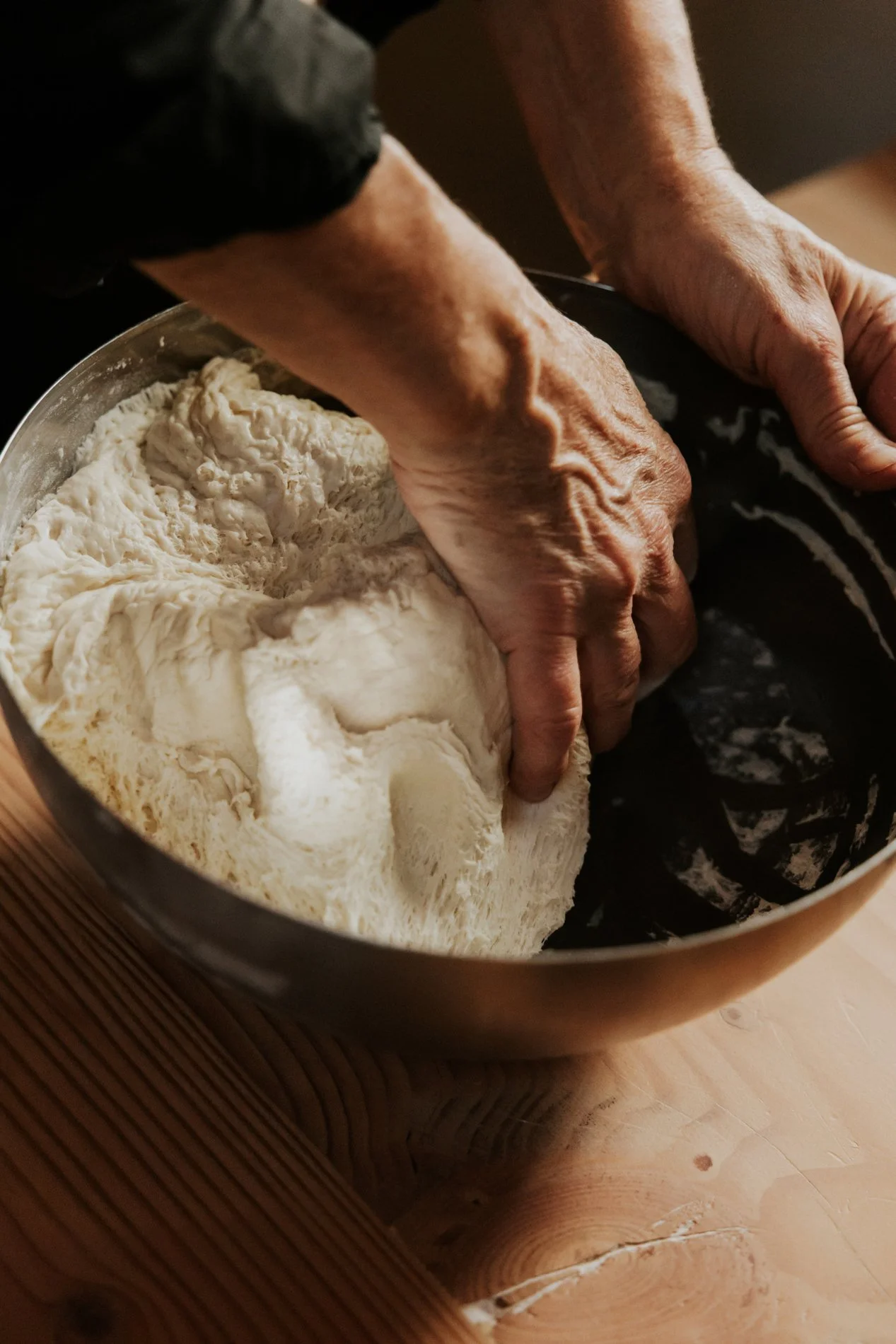 Hand die deeg kneed voor pizza in een grote keramieken kom.