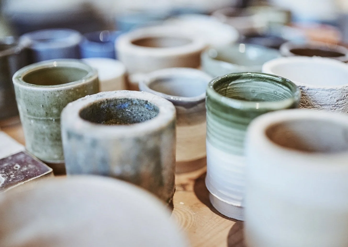 Geglazuurde potten in diverse vormen en kleuren op een houten tafel.