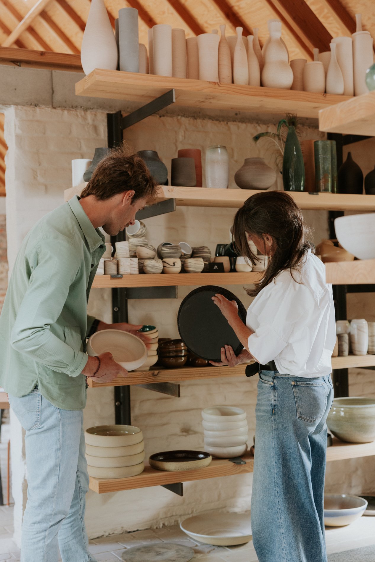 Twee personen die keramische handgedraaid servies aan het bekijken zijn