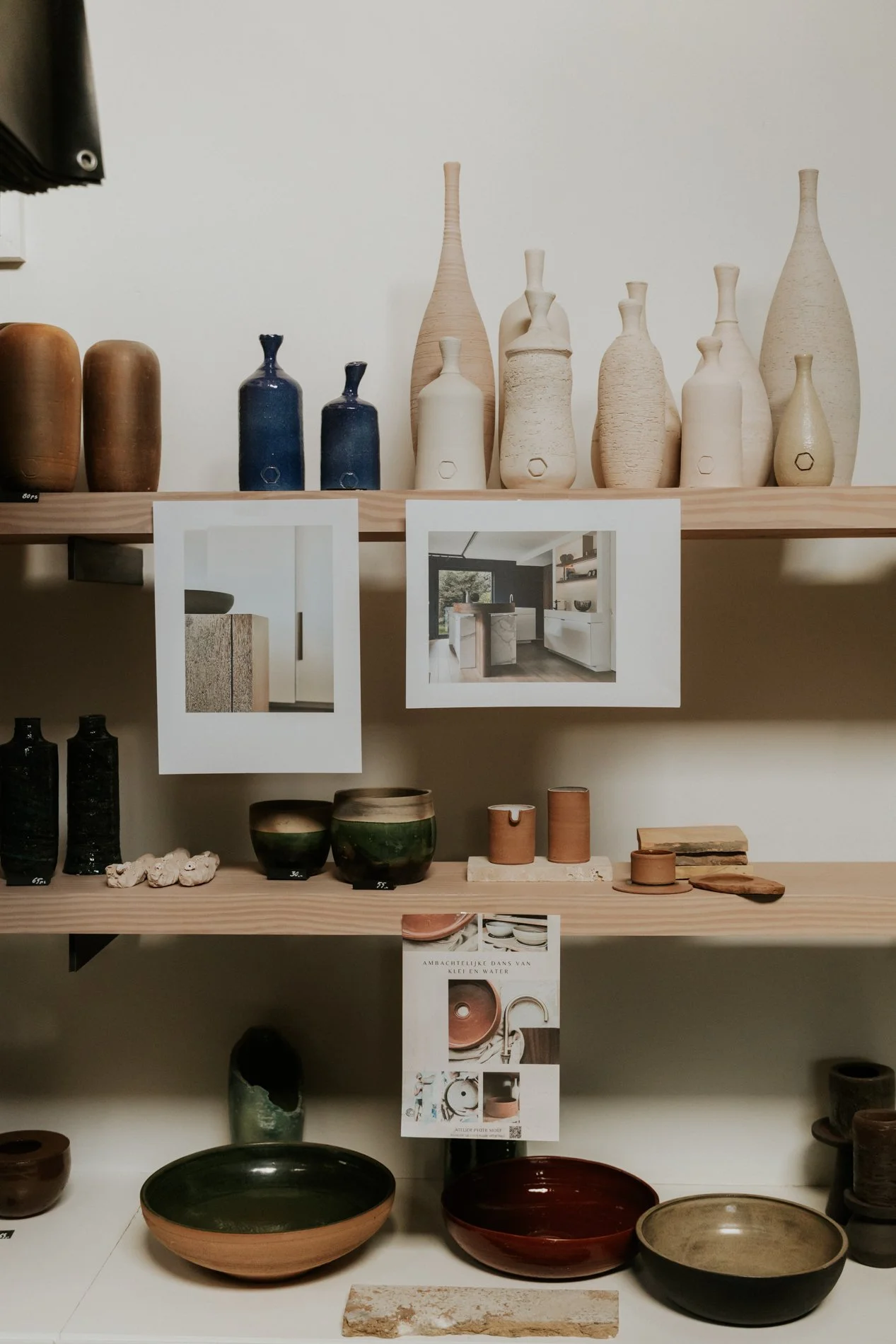 Houten rek in een atelier met diverse keramieken objecten in maatwerk er op gepresenteerd met diverse kleuren. Atelier Pyotr Morf.