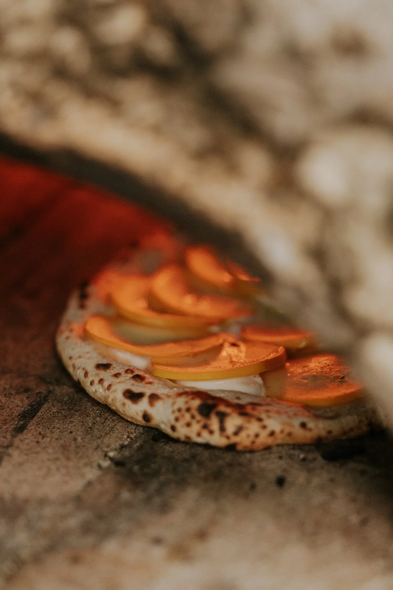Pizza die afgebakken wordt in een houtoven.Zicht op het vuur.