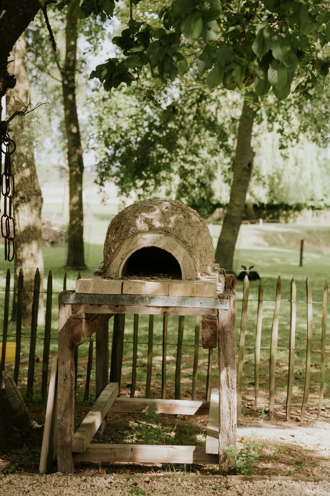 Klei hout oven met op de achtergrond een weide met een zwart schaap in.