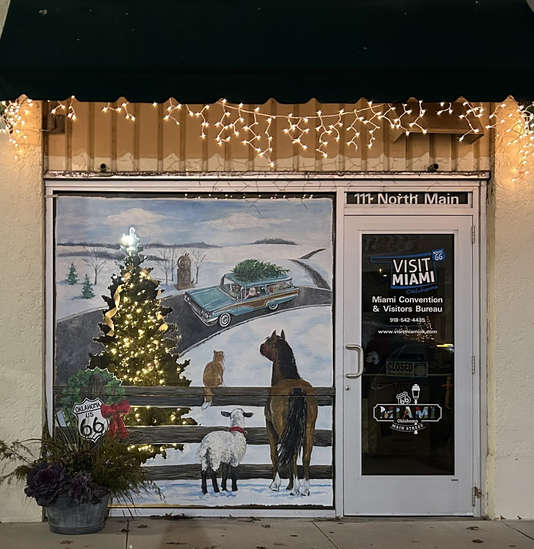 Holiday Window Art at Miami OK Convention & Visitors Bureau in the evening with interior tree lights glowing through the design. 7.5'x 6.5'. 2025.