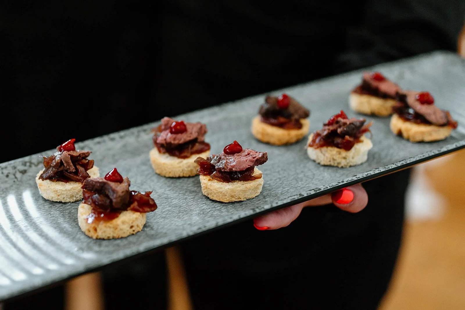 Short rib bites on rice crackers with gochujang sauce on a serving platter.