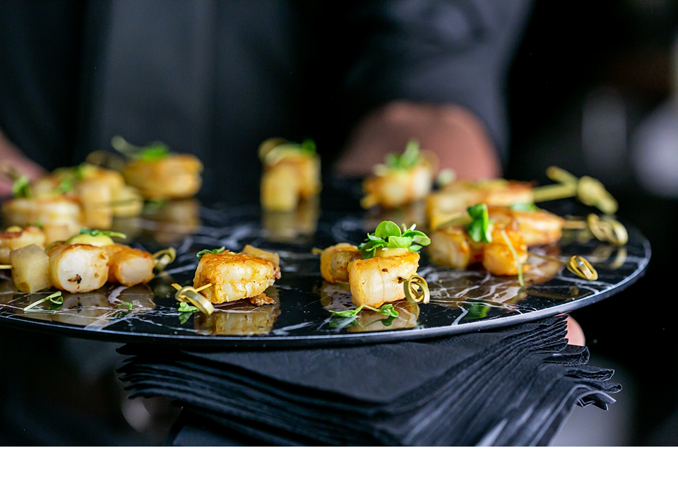 Shrimp skewers with curry seasoning on a black marble platter with toothpicks.