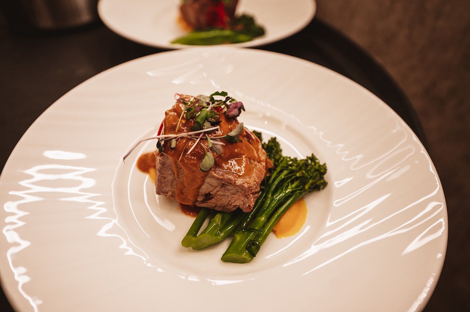 Grilled steak meal with brown sauce and broccolini.